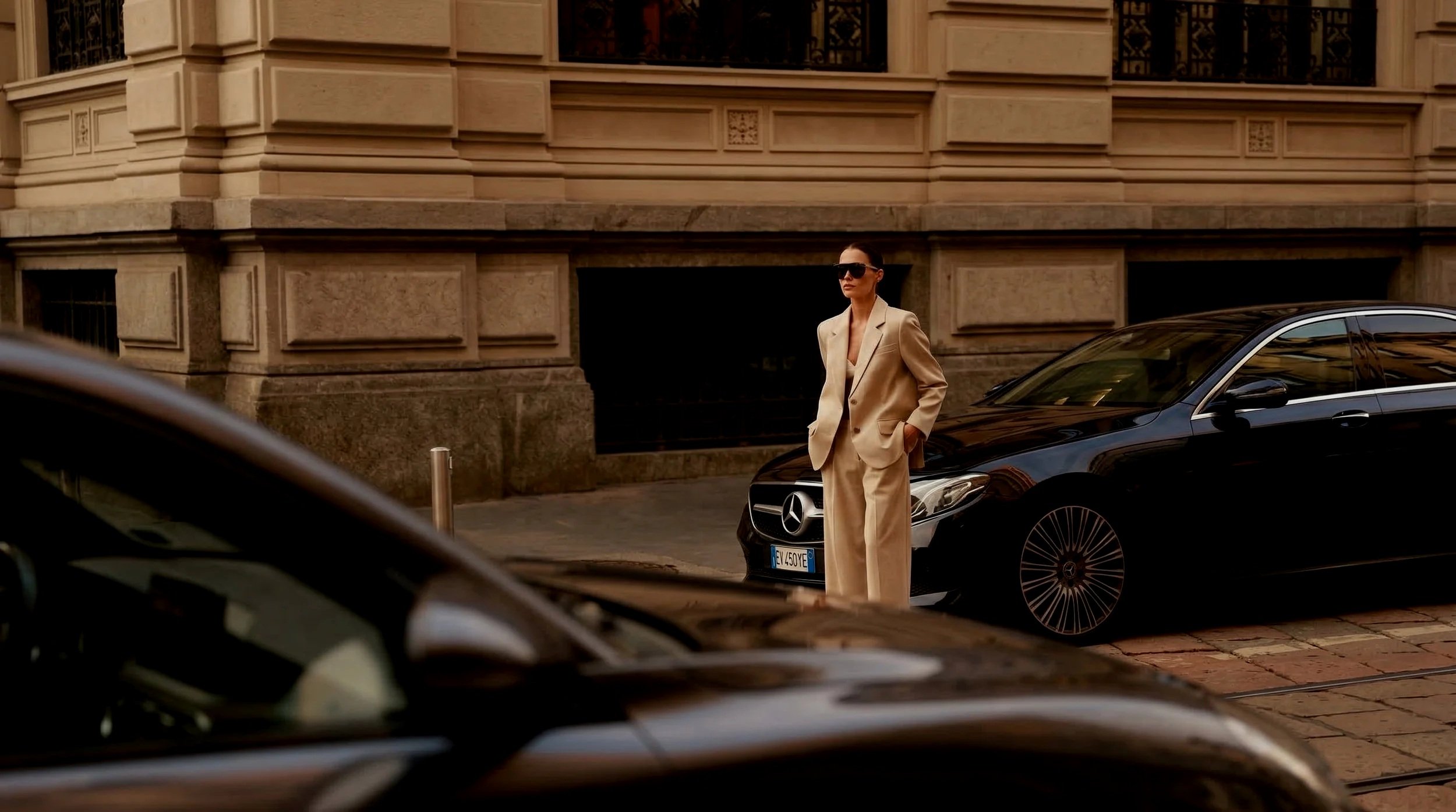 High-level female executive with a luxury vehicle in historic Lausanne, Switzerland — Swiss Premier recruitment.