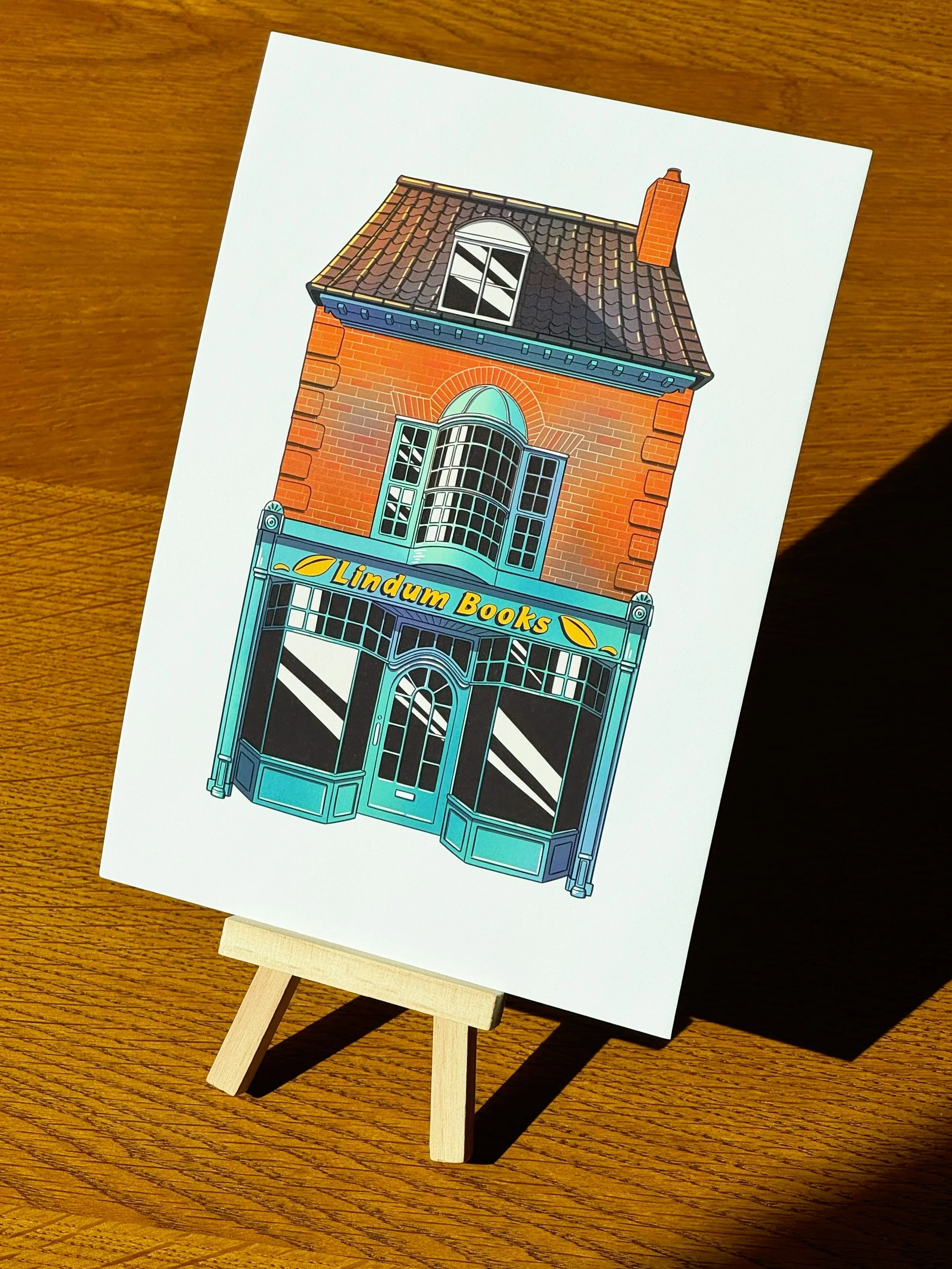 Illustration of a bookstore storefront called Lindum Books with a red brick building and a large sky-blue window display.
