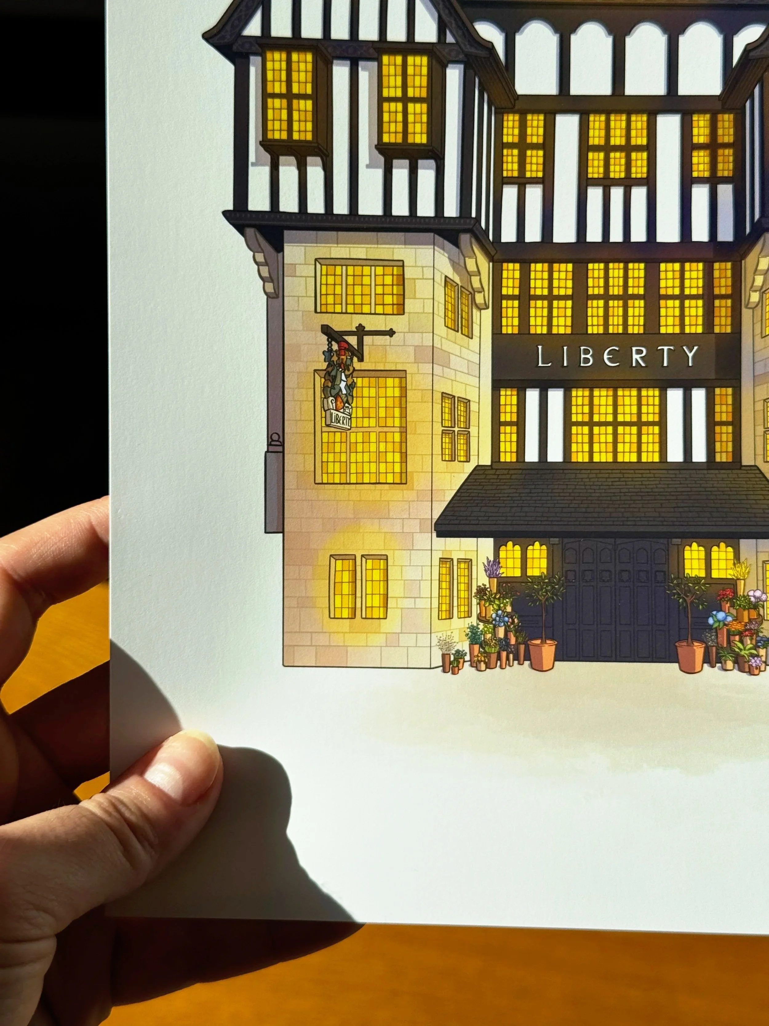 Illustration of a building with multiple floors, with windows illuminated from inside, and a sign reading 'LIBERTY' on the front. There are potted plants outside the entrance.