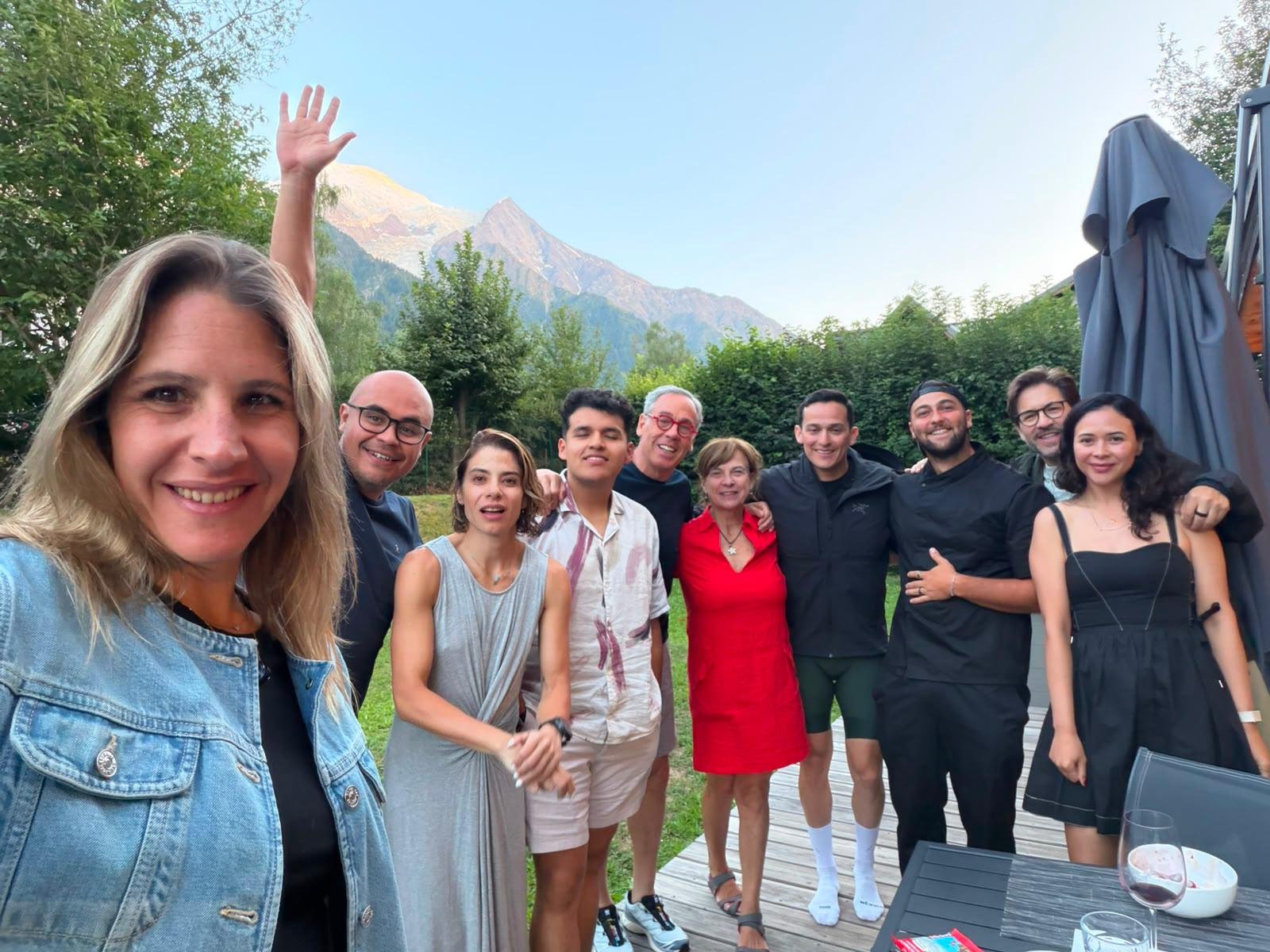 Groupe de personnes souriantes en extérieur avec montagnes en arrière-plan.