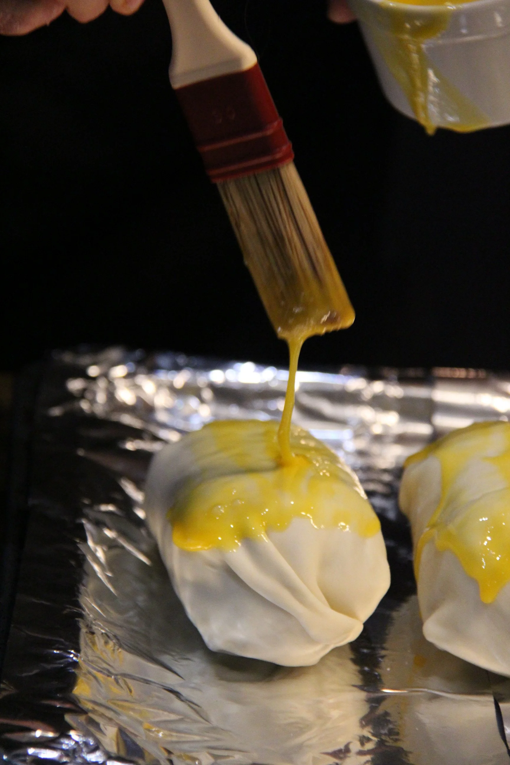 Préparation du bœuf Wellington, jaune d'oeufs appliqués au pinceau sur la pâte feuilletée. 