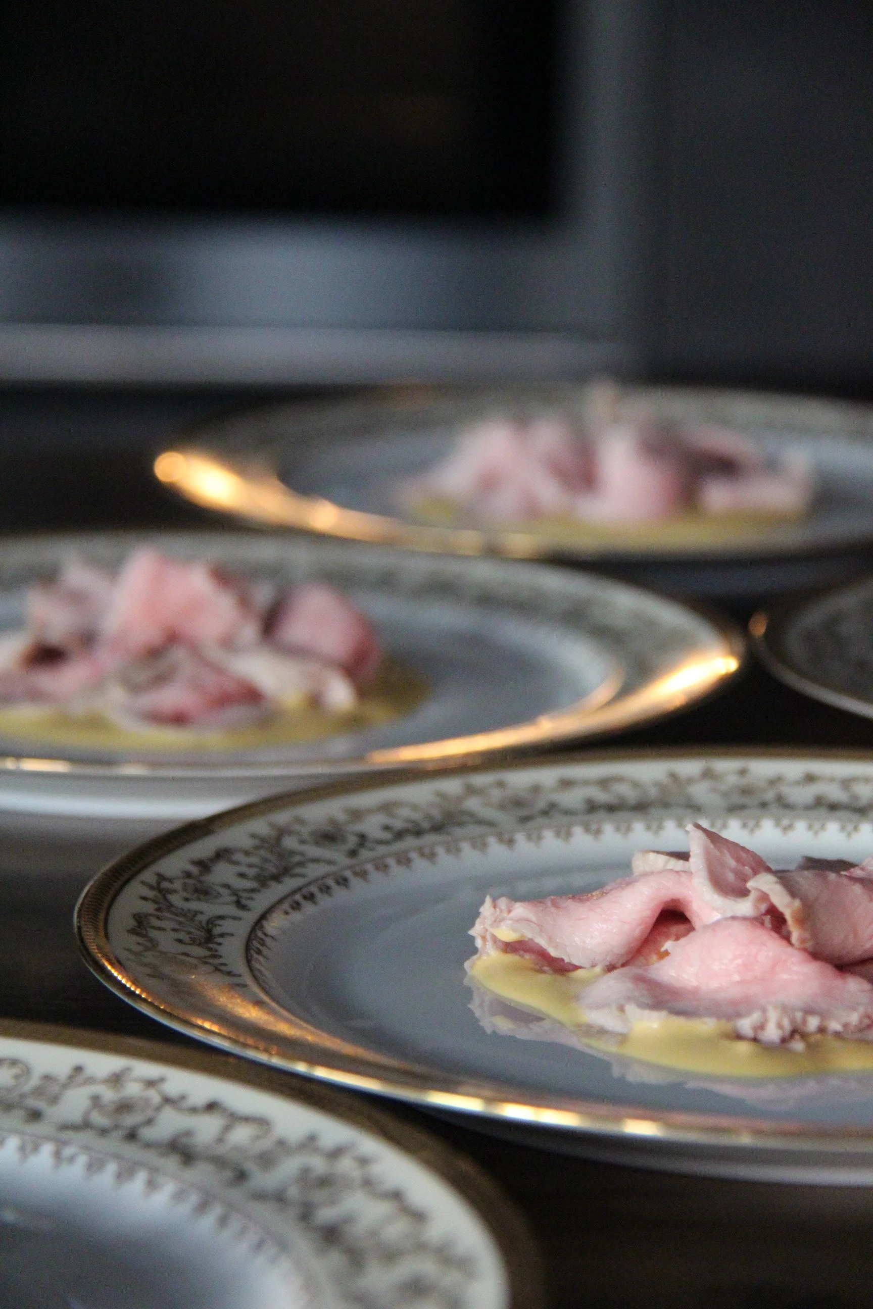 Vitello Tonnato sur des assiettes en porcelaine ornée de dorure.