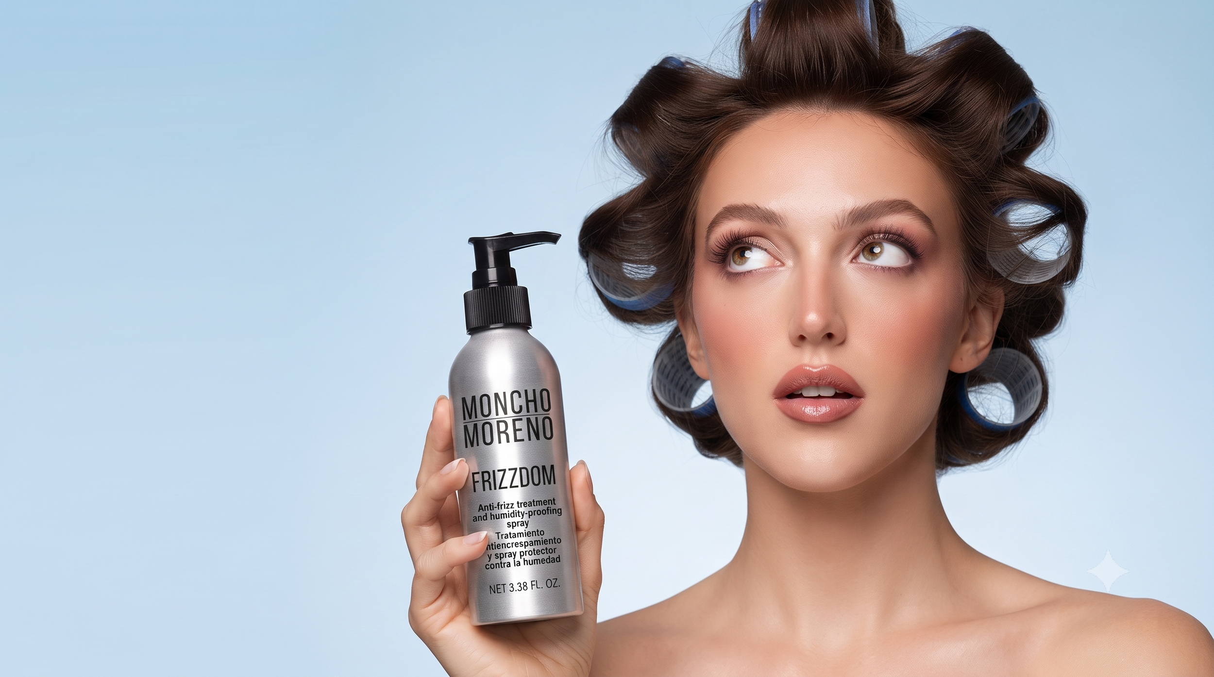 A woman with styled hair and makeup holding a silver spray bottle labeled 'MONCHO MORENO FRIZZDOM' against a light blue background.