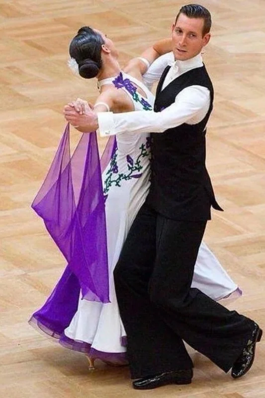 Tanzpaar in formeller Kleidung beim Tango auf einem Holzboden.