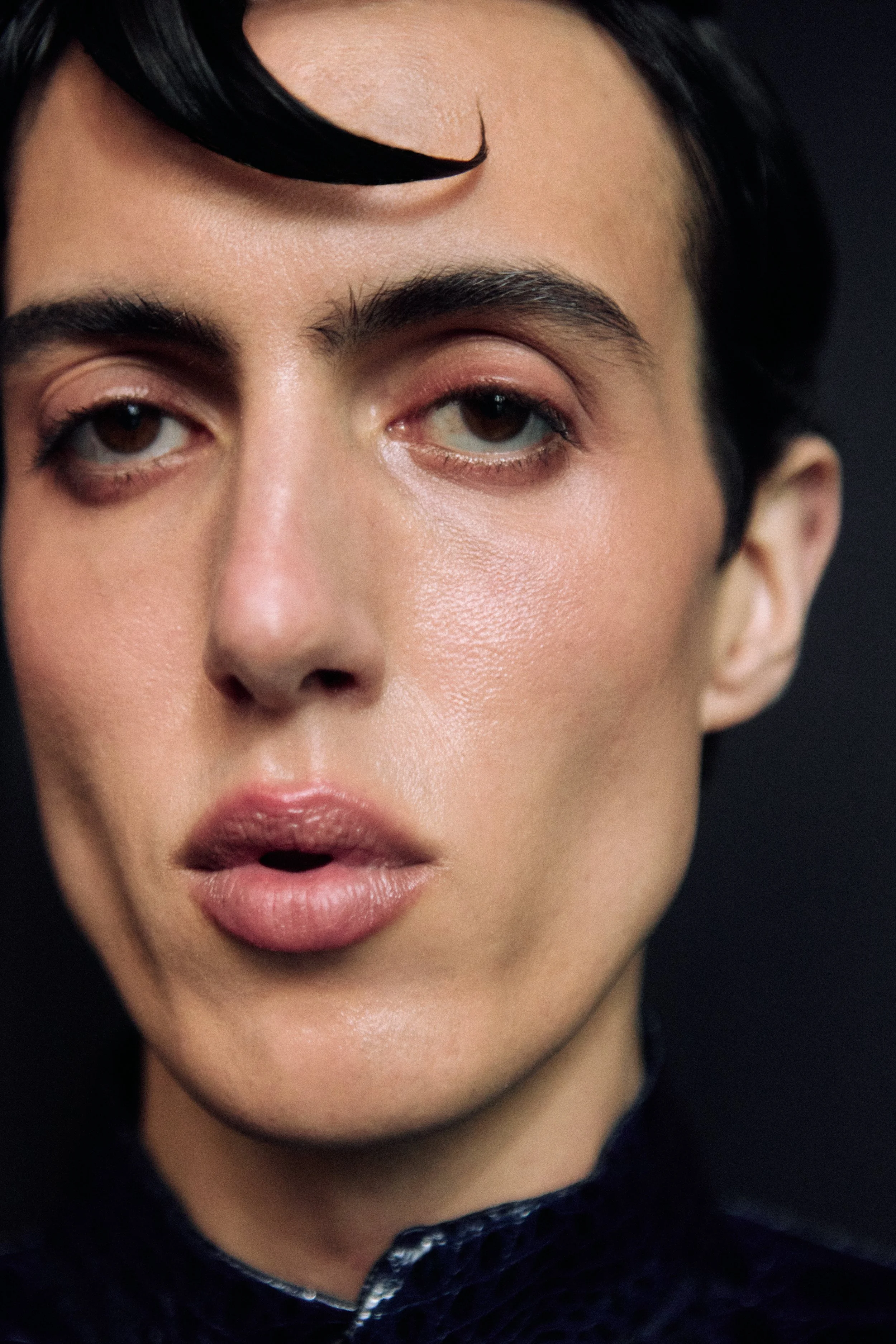 Close-up of a person's face, showing the area from the eyebrows to the mouth. The person has dark hair, well-defined eyebrows, and light skin. Their eyes are partially open, and their lips are slightly parted.