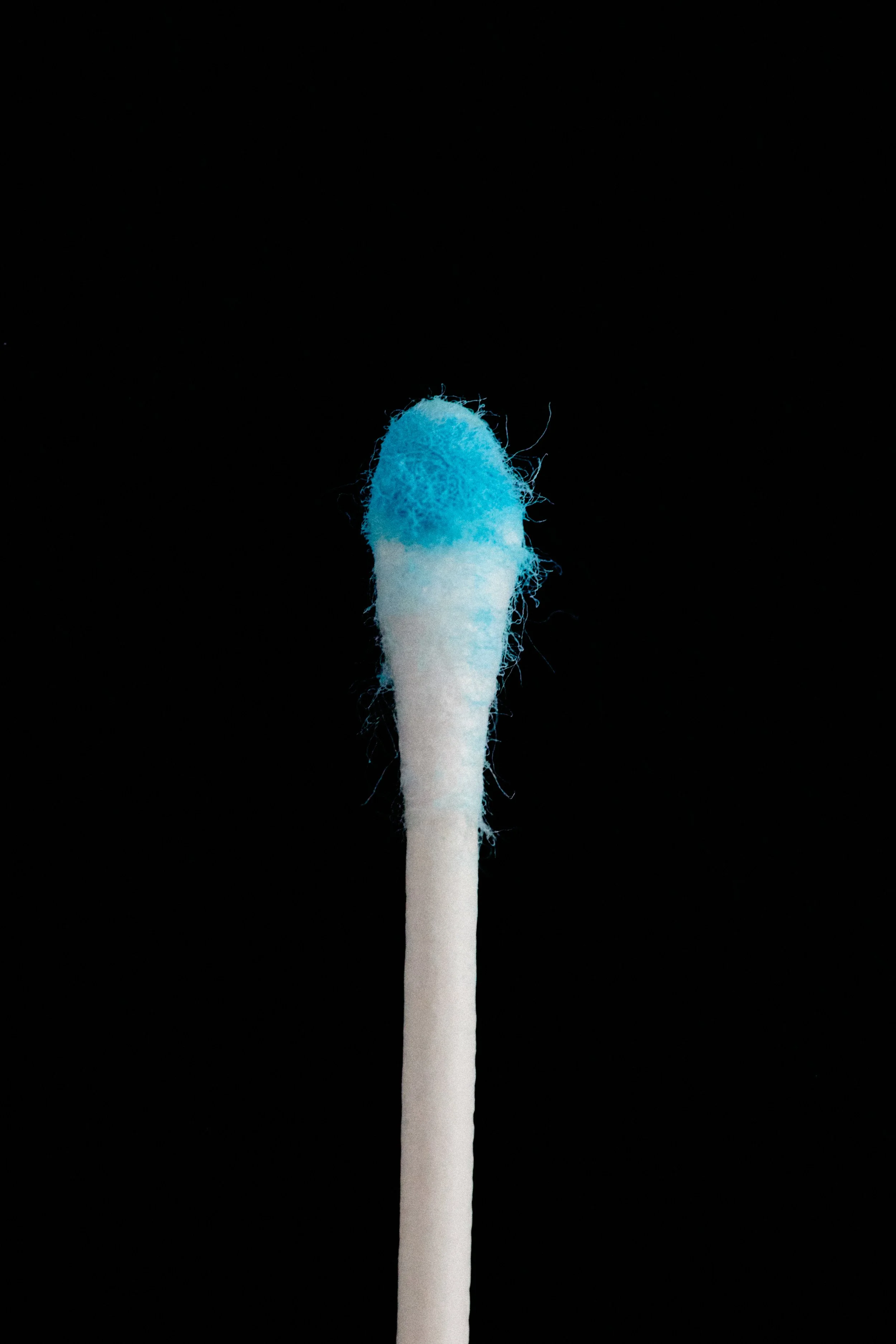 Close-up of a blue-tipped matchstick on a black background.