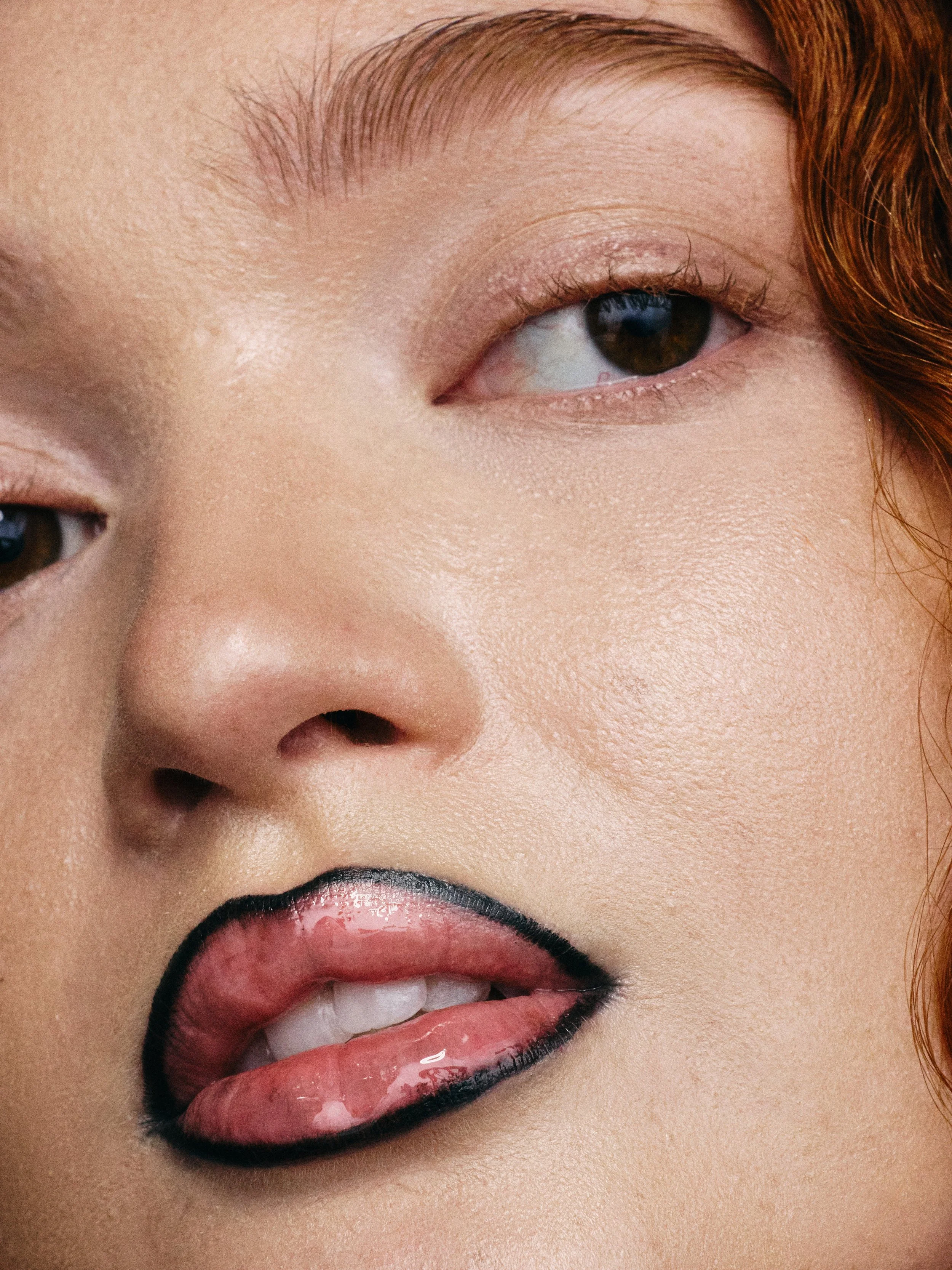 Close-up of a woman's face, focusing on her right eye, partial nose, and lips with black lipstick.