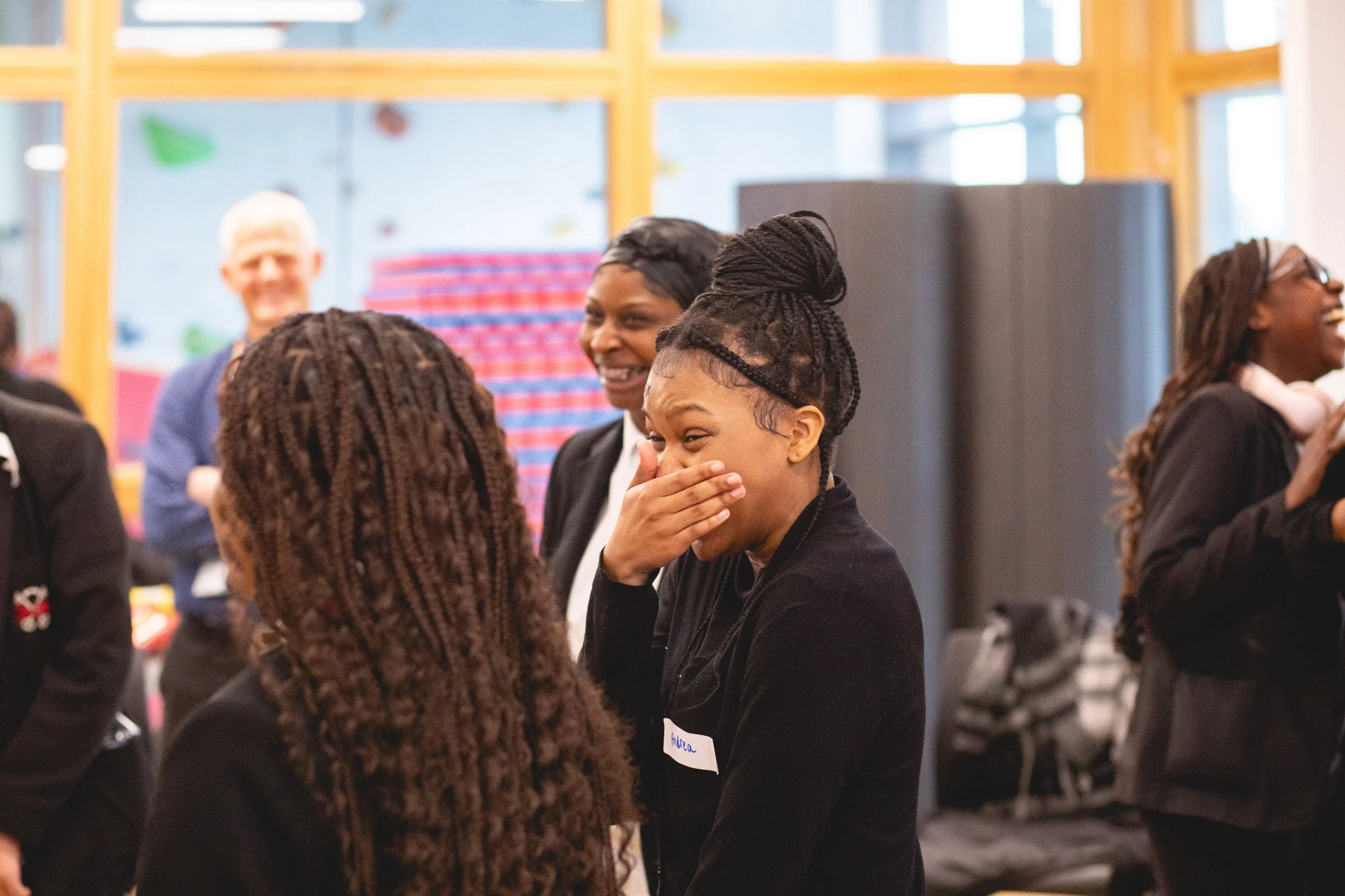 A group of diverse people smiling and talking at an indoor gathering or event.