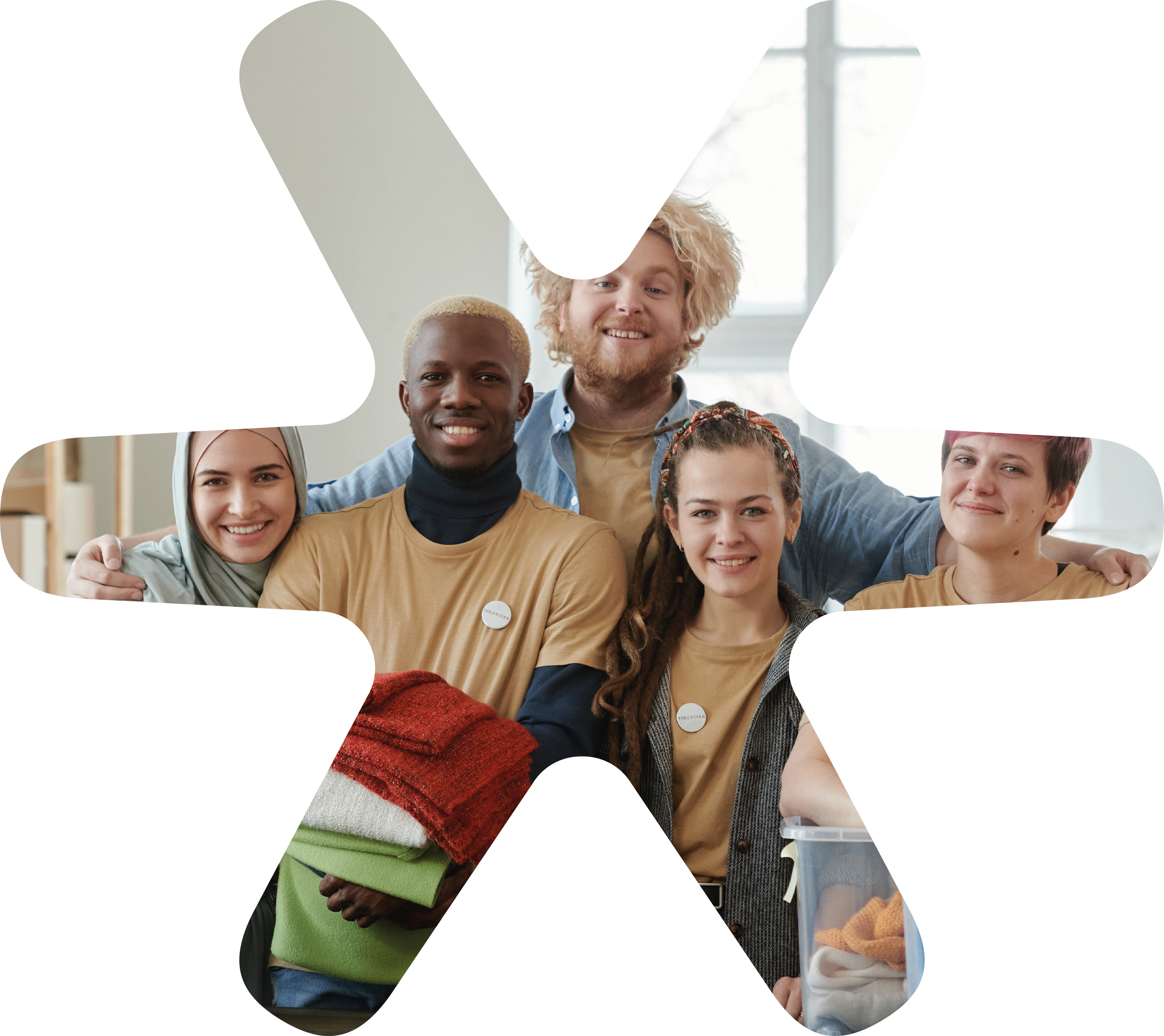 Smiling diverse group of people posing together indoors, some with folded arms, in a well-lit room with large windows.