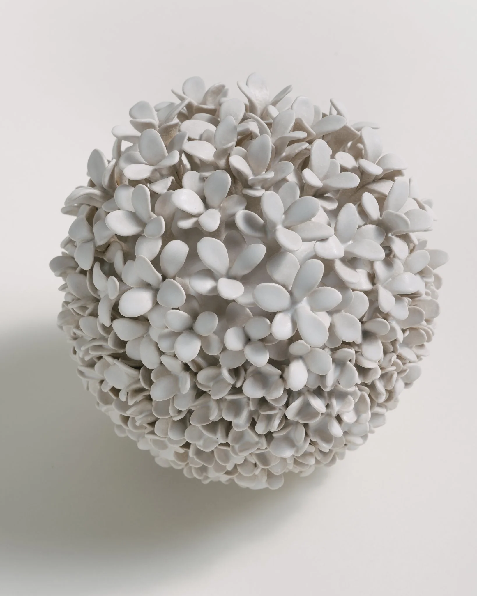 Close-up of a cluster of white flower-shaped ceramic or plastic decorative items on a plain white background.