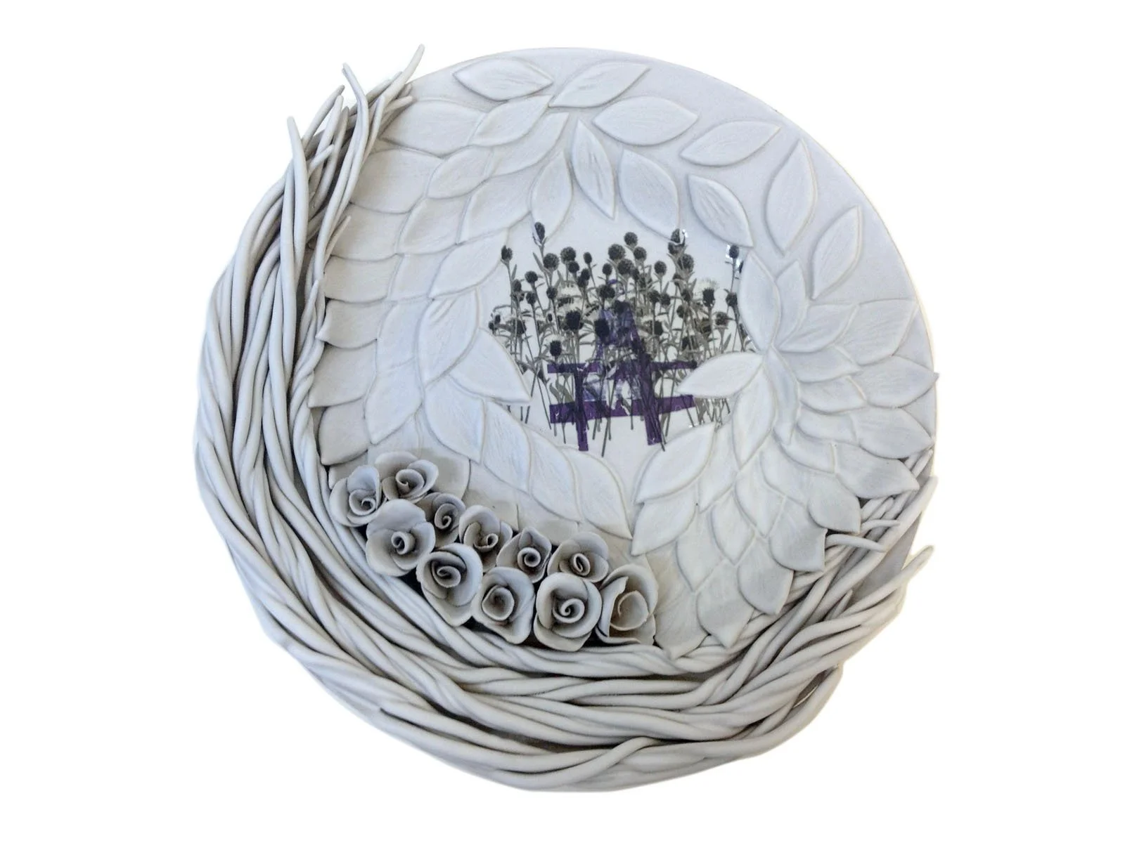 Decorative white bowl with intricate leaf and rose designs, containing a printed image of dried flowers and a bench.