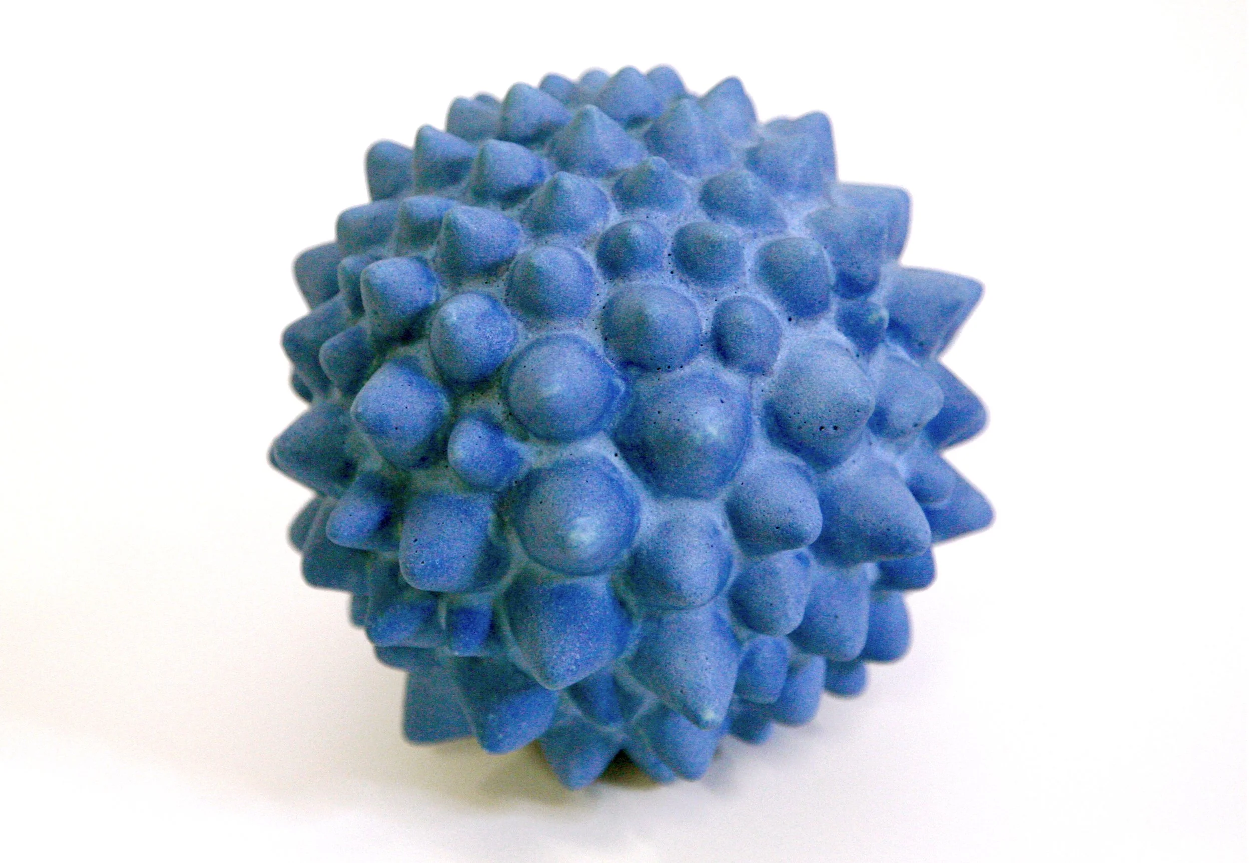 Close-up of a blue spiky massage ball on a white surface.