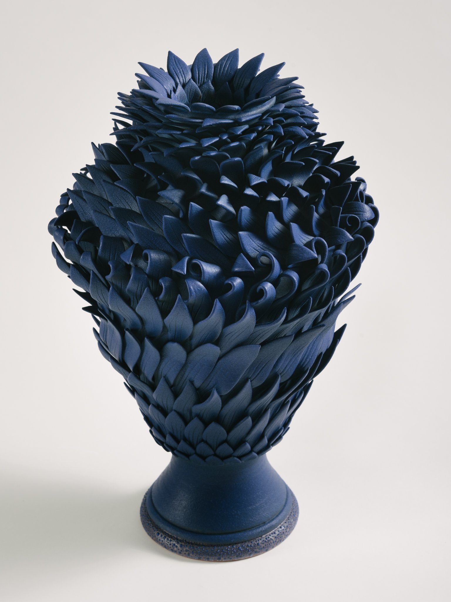 Blue textured sculpture resembling a blooming flower on a round base.