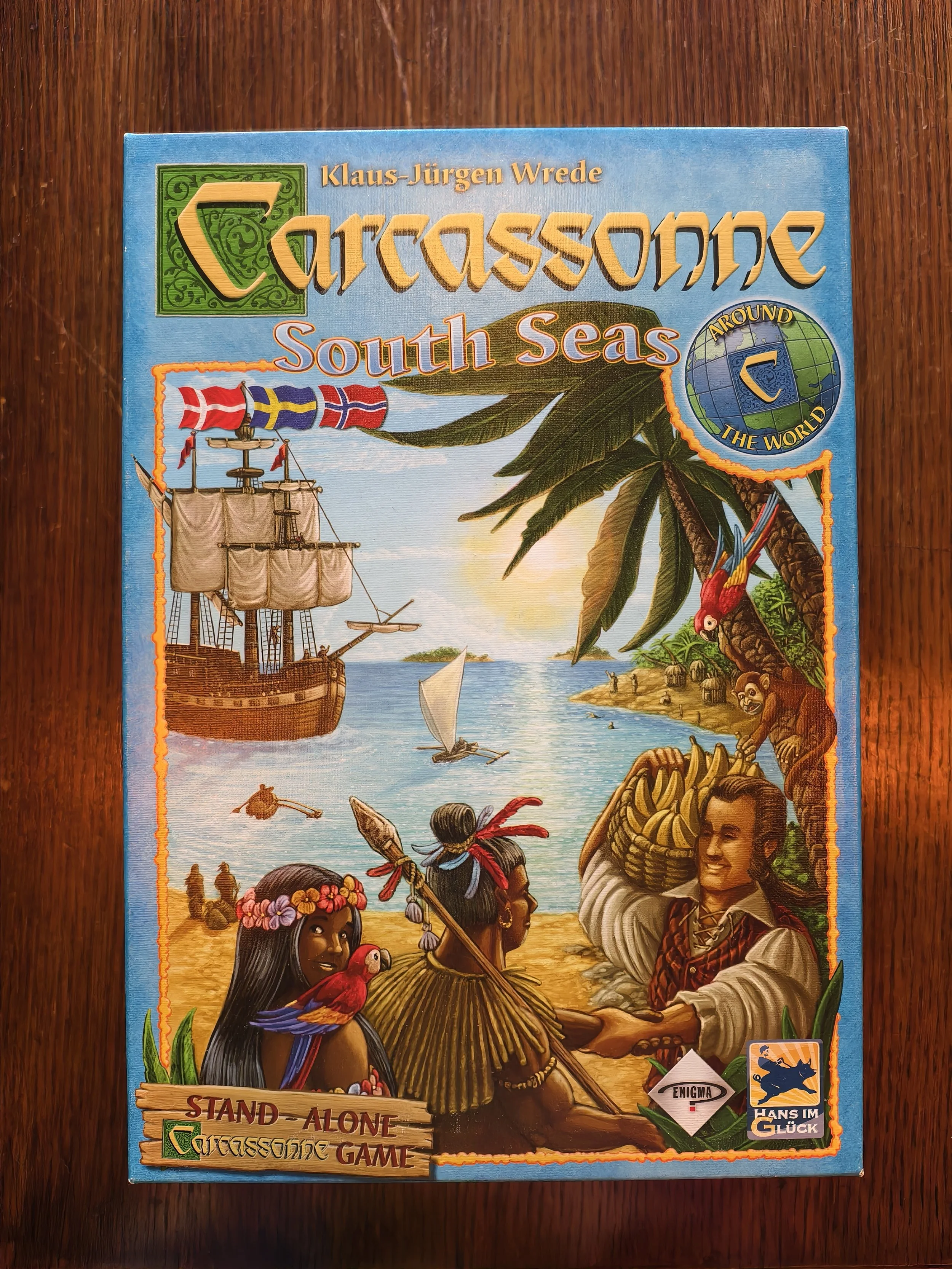 Board game titled 'Carcassonne: South Seas' by Klaus-Jürgen Wrede with tropical island and sailing ship artwork, featuring people in traditional Polynesian attire and tropical scenery.