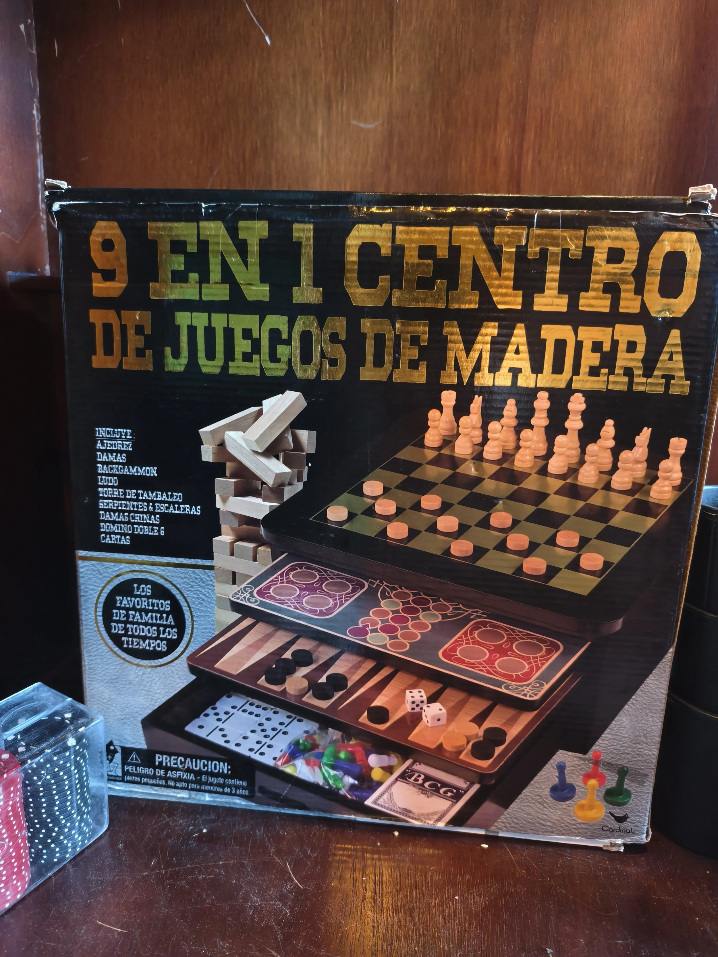 Board game set with a chess board, checkers, dice, and various game pieces on a dark wooden table.