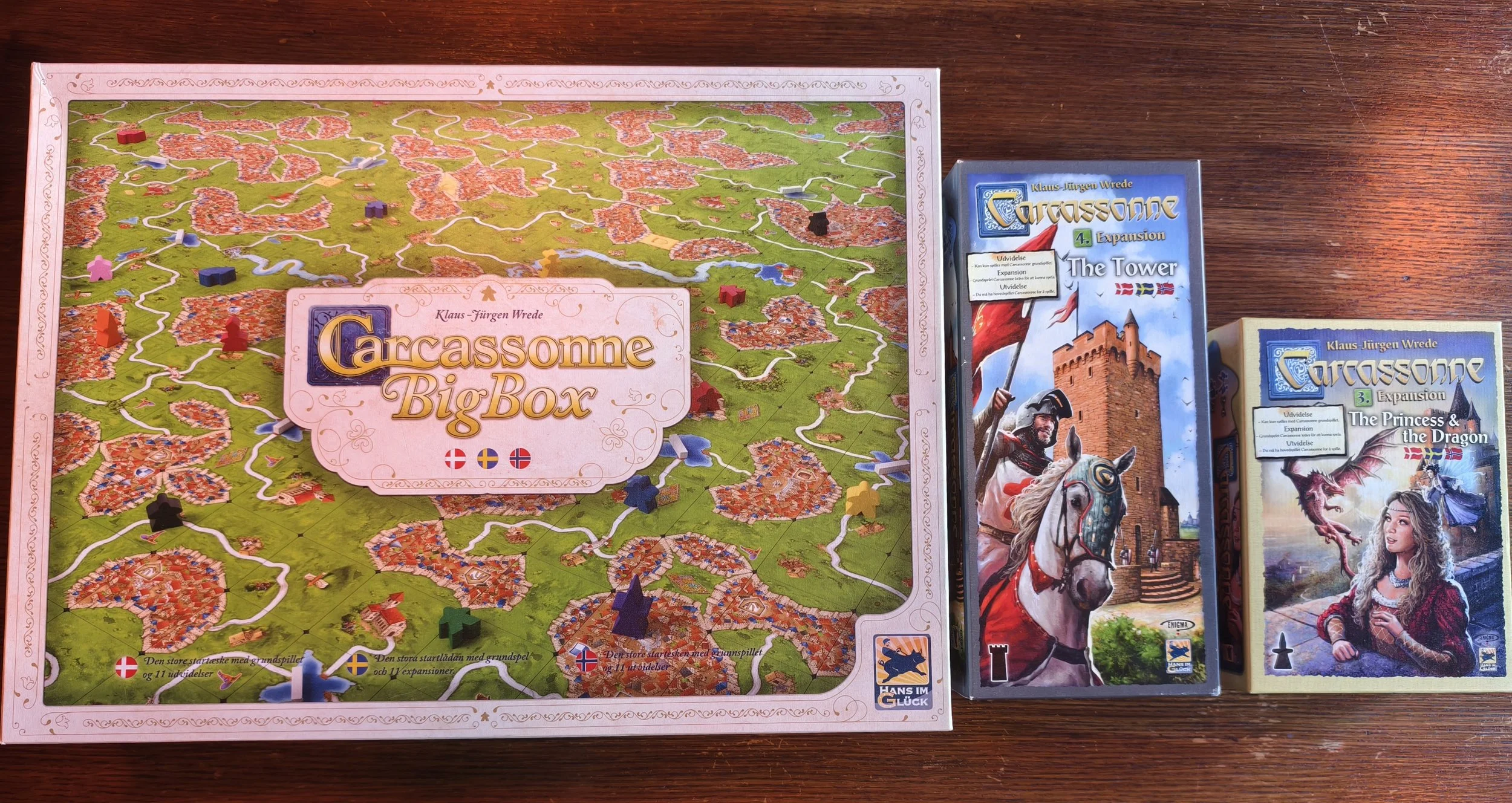 Top view of Carcassonne Big Box and expansion game boxes on a wooden surface.