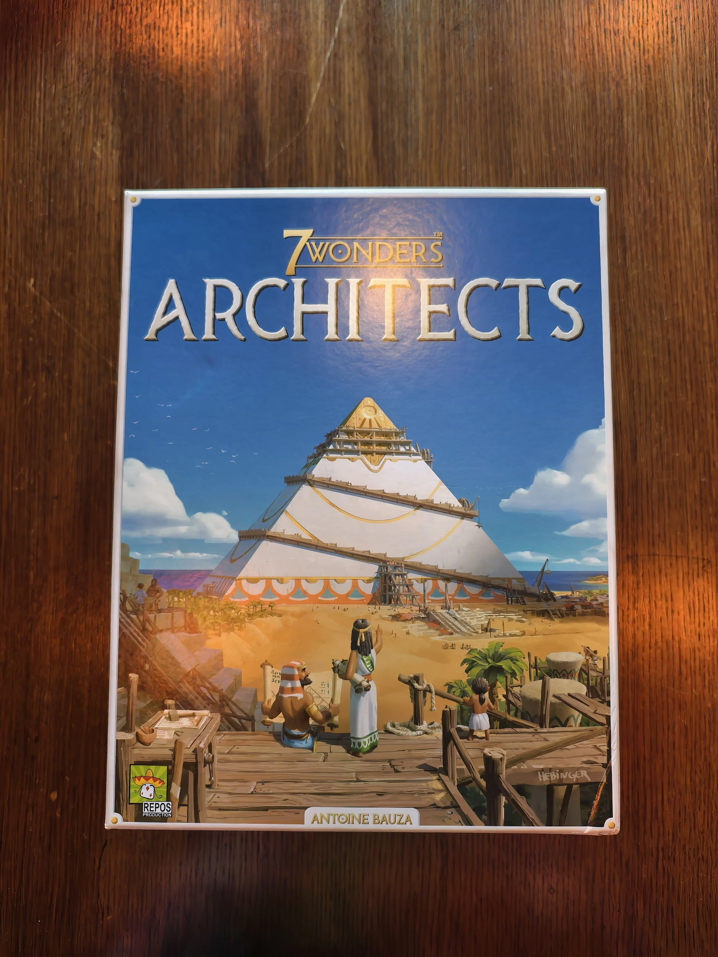 Board game box art for '7 Wonders Architects' featuring an illustration of a large Mayan or Aztec pyramid with people and animals in front, set against a bright blue sky with clouds.