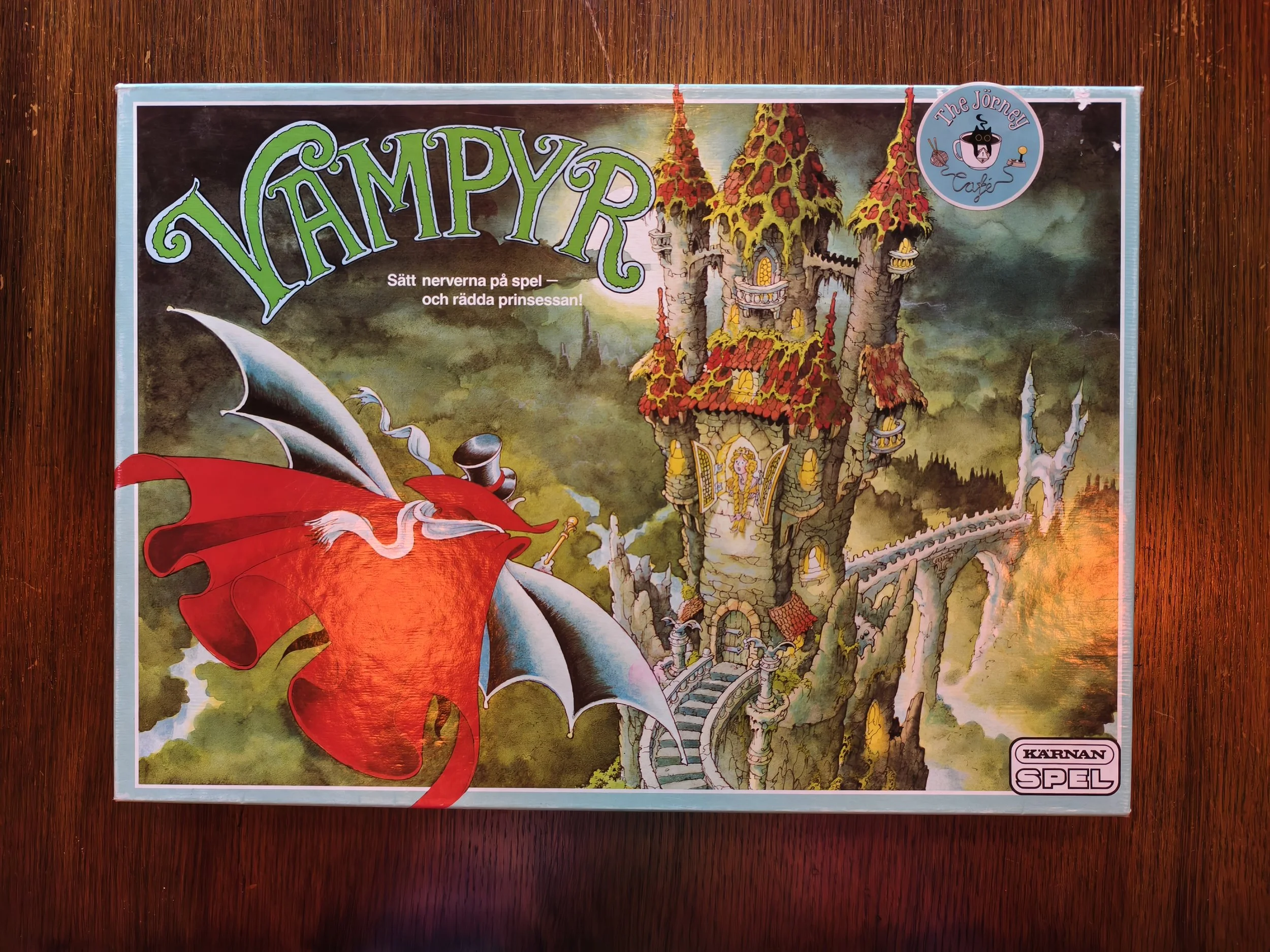 A colorful board game titled 'Vampyr' with an illustration of a haunted castle and a red cape on a wooden surface.