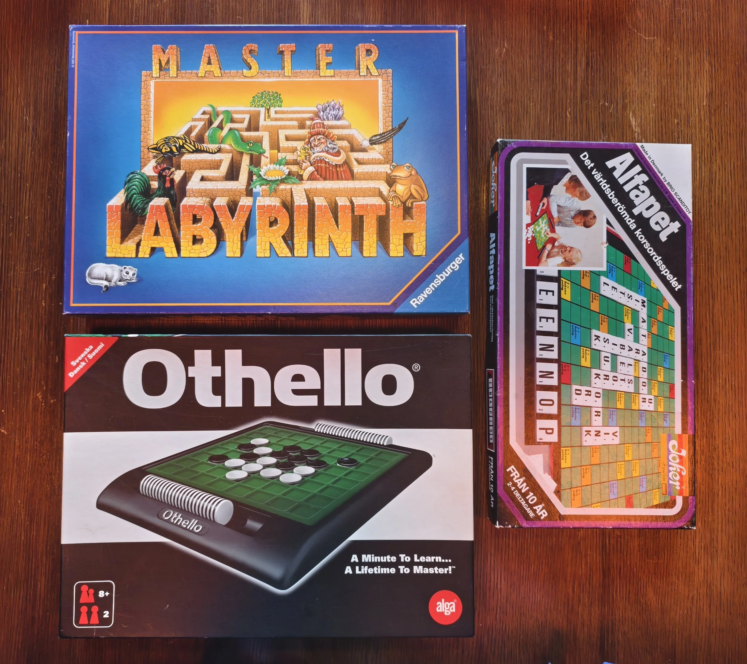 Board game titled 'Master Labyrinth' showing a maze with themed illustrations of a snake, crocodile, owl, and wizard, and a game box for Otello, a checkers game, on a wooden surface.