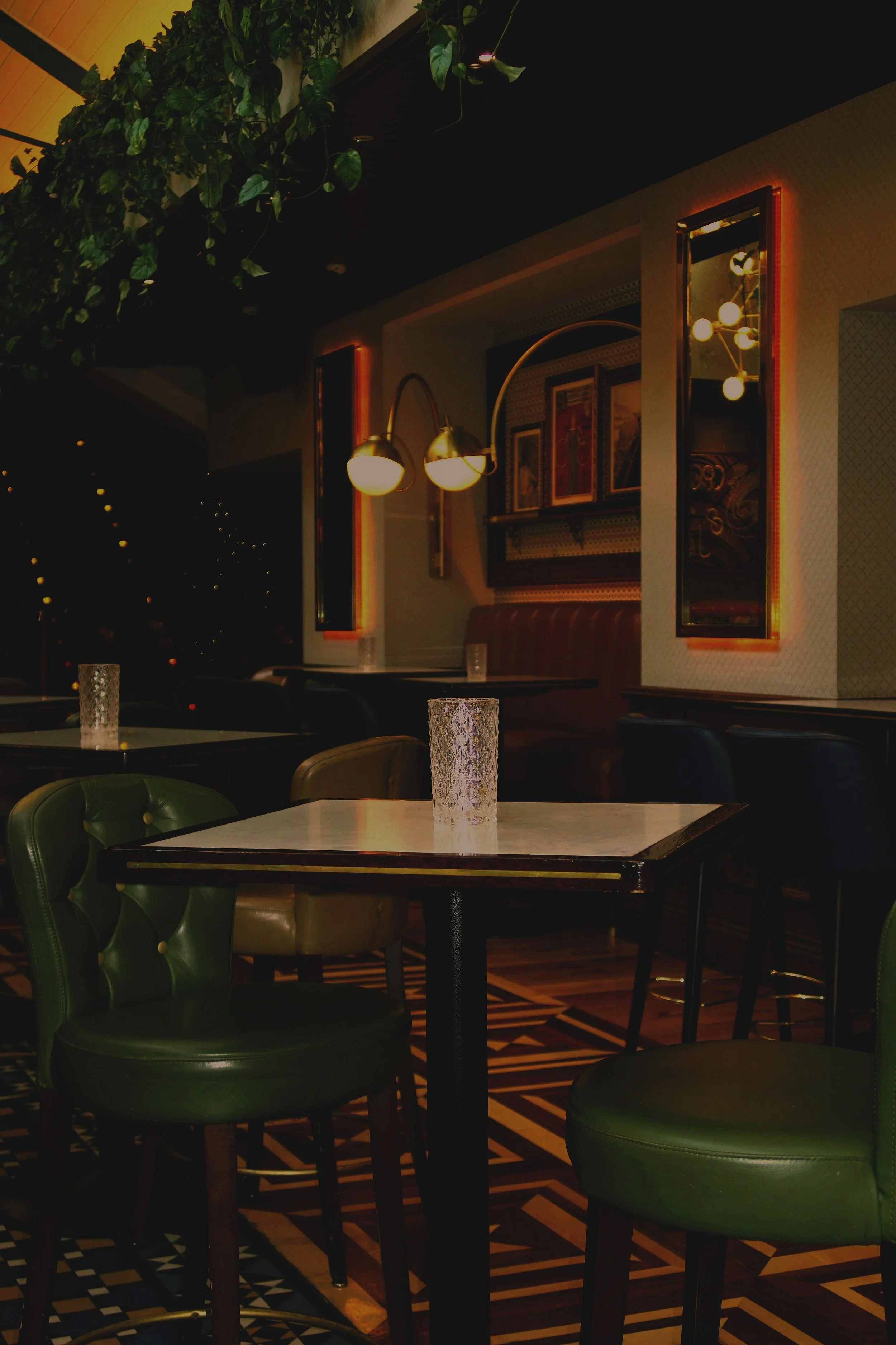 A wall covered in lush green tropical plants with a neon sign that says 'Smile' in the center.