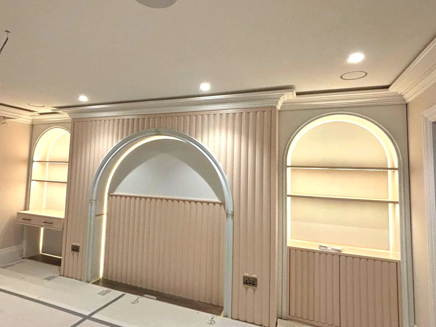 Interior wall with built-in shelves and decorative arches, illuminated with soft, warm lighting.