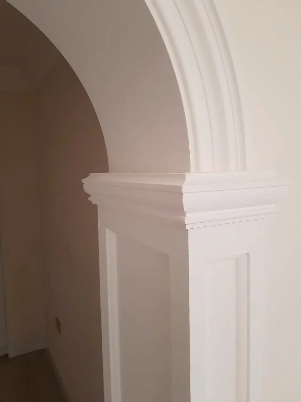 Close-up of a decorative white architectural molding on a wall and arched ceiling.