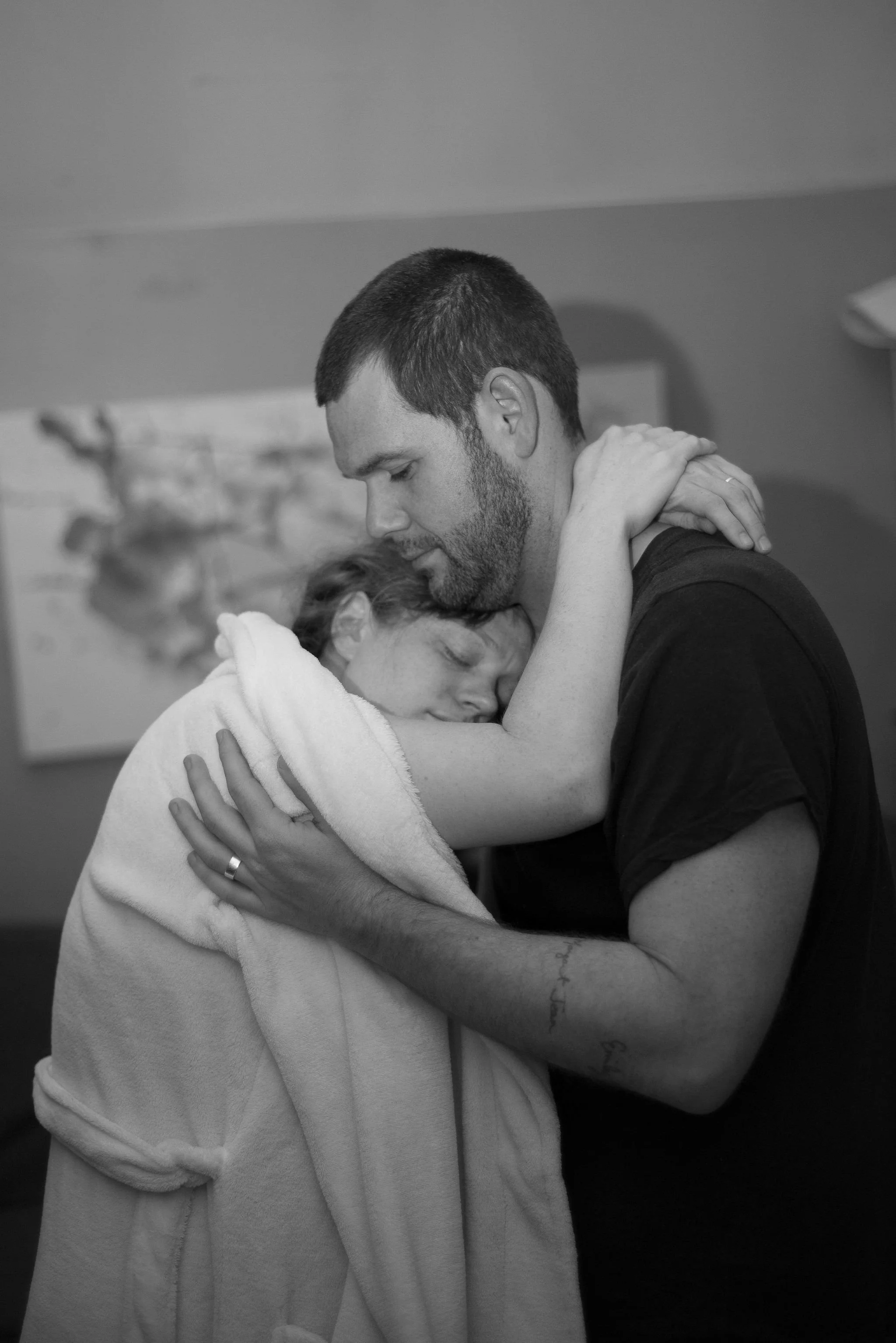 A man and woman sharing an intimate embrace, with their eyes closed, in a comforting hug during labor.