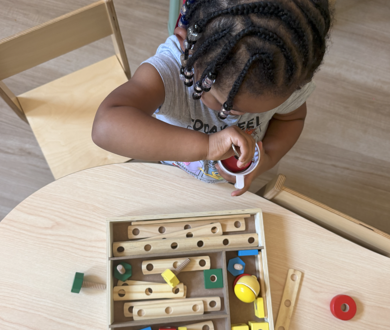 A young child sitting at a wooden table playing with wooden blocks.