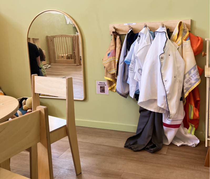 Clothing rack with kids dress up clothes in a children's play area.