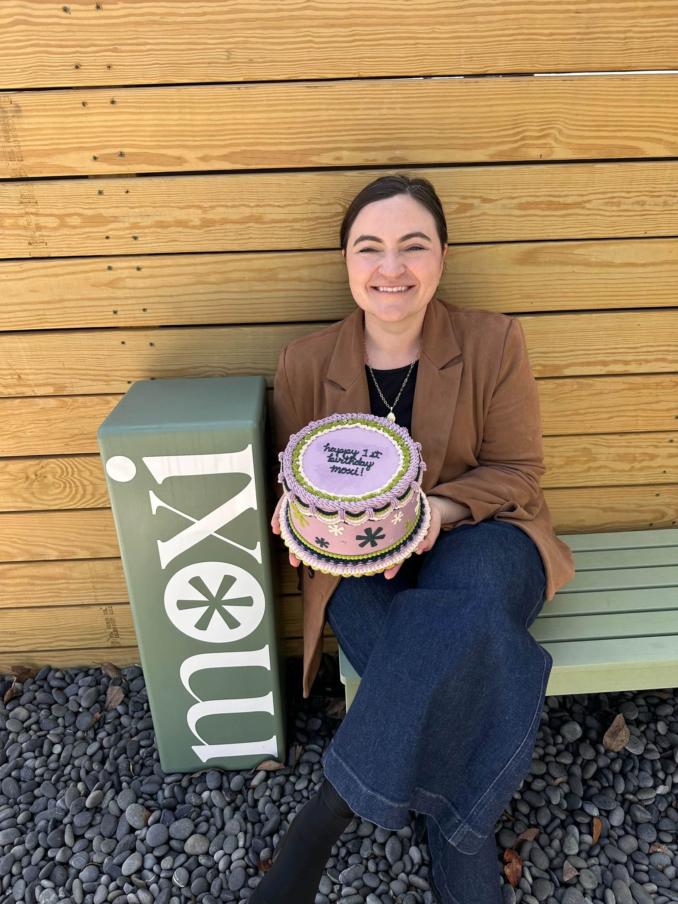 Photo of Cori Fain-Forrest, founder and CEO of Moxi, holding a Moxi birthday cake