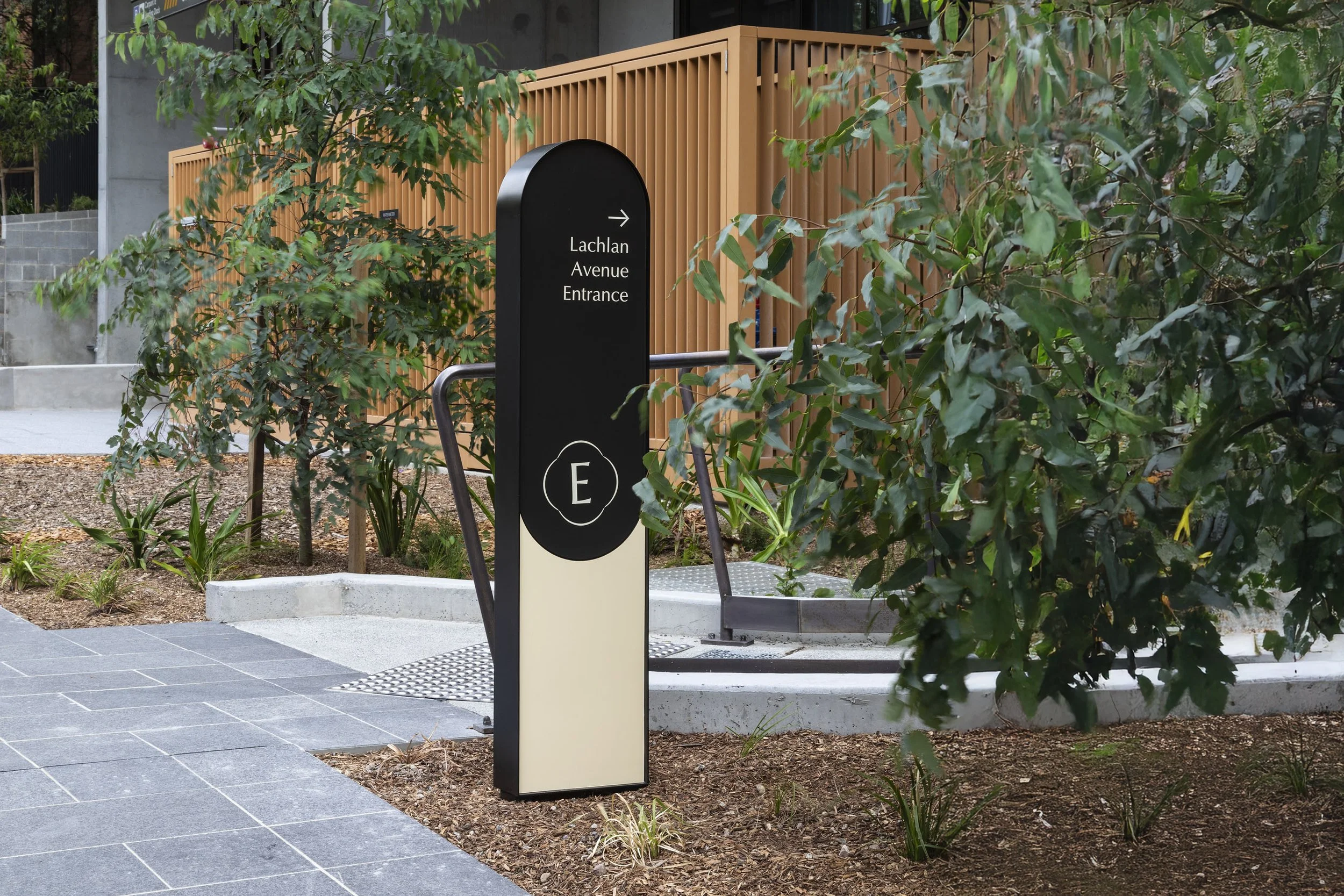 Entrance sign for Lachlan Avenue, with greenery and a modern building in the background.