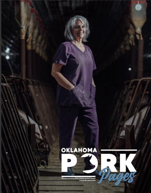 Cover of Oklahoma Pork Pages featuring a smiling woman with gray hair wearing purple scrubs standing in a pig farm barn, with pig pens on either side and the text 'Oklahoma Pork Pages' overlaid.