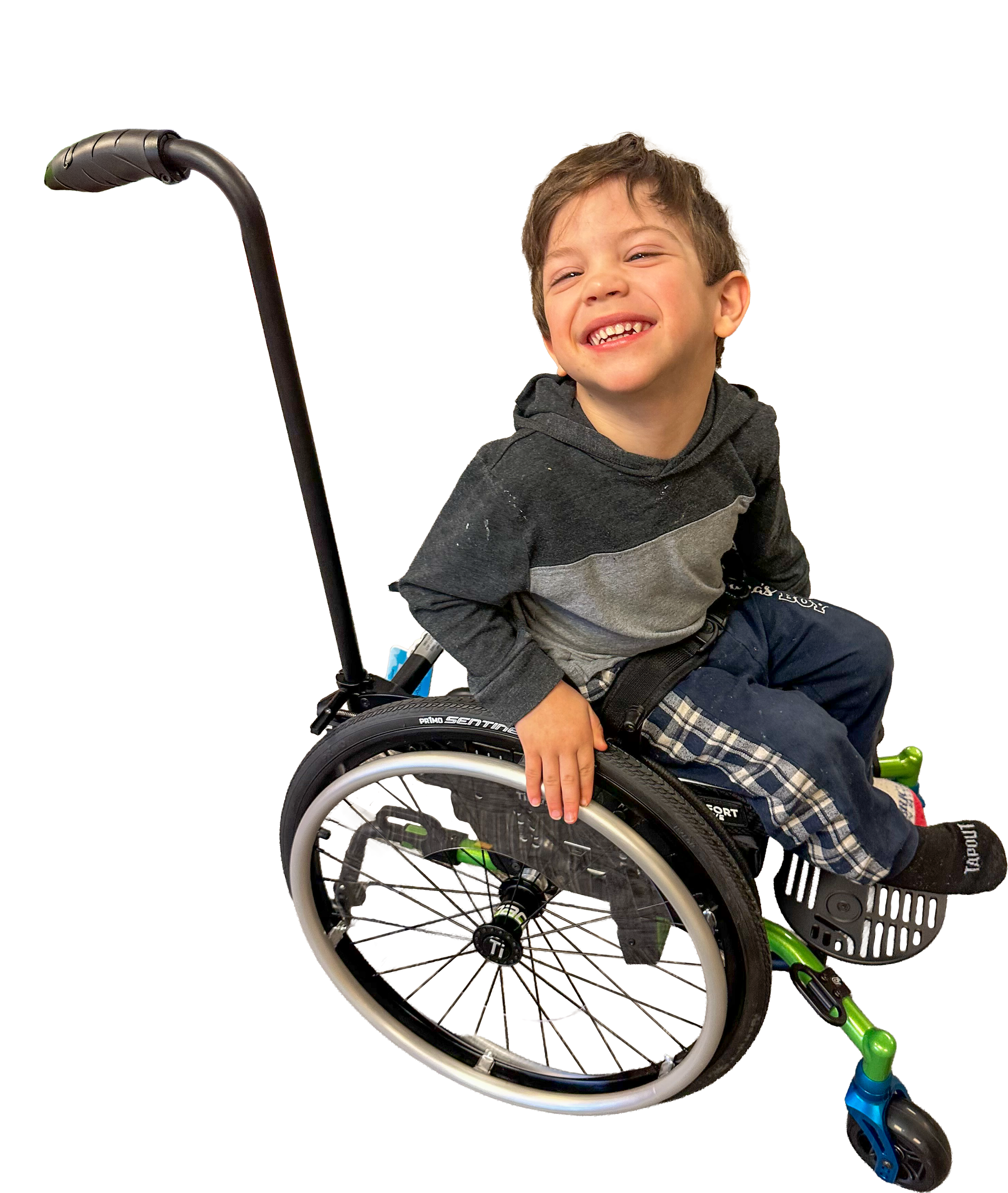 A young boy with brown hair smiling while sitting in a green and black wheelchair, wearing a gray and black hoodie, with a colorful scooter in the foreground.