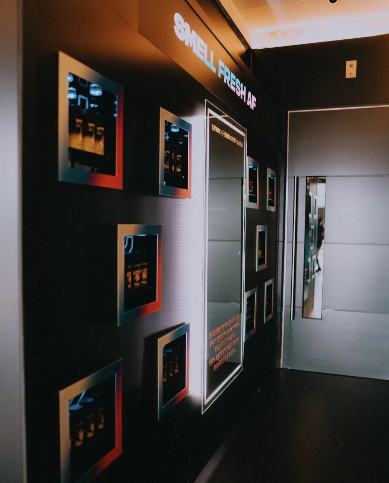 Digital displays with advertisements in an elevator lobby, featuring logo and promotional text for Shell and cigarettes.