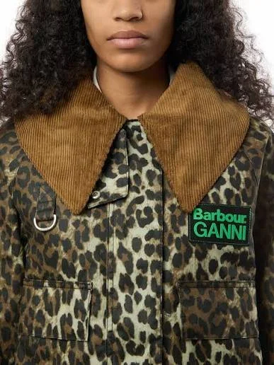 Close-up of a woman wearing a leopard print jacket with a brown corduroy collar and a green and black GANNI logo patch.