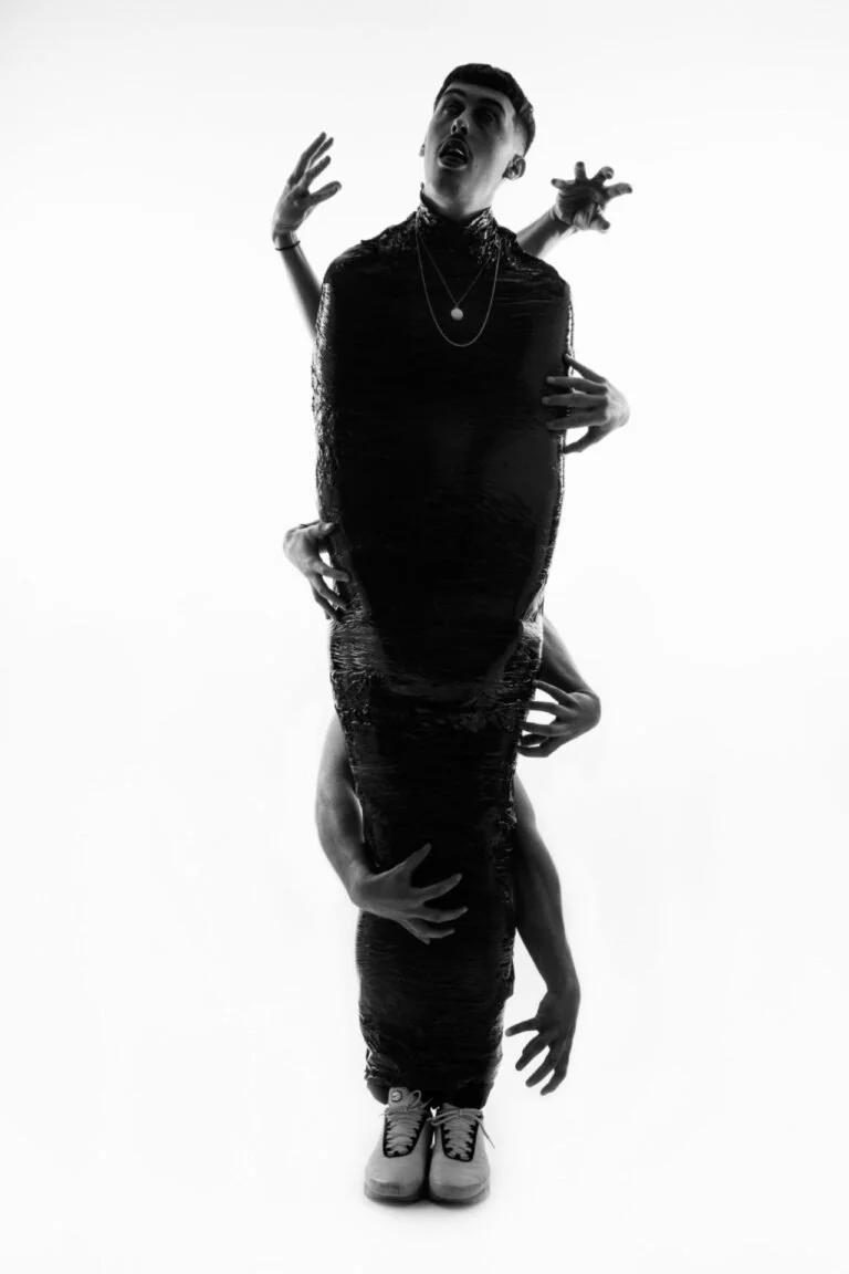 Une figure humaine portée par plusieurs mains en perspective et en miroir, créée dans un style artistique monochrome noir et blanc.
