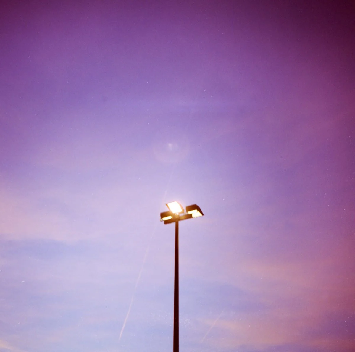 Un lampadaire sous un ciel étoilé avec des nuances de violet et de bleu, et des étoiles visibles.