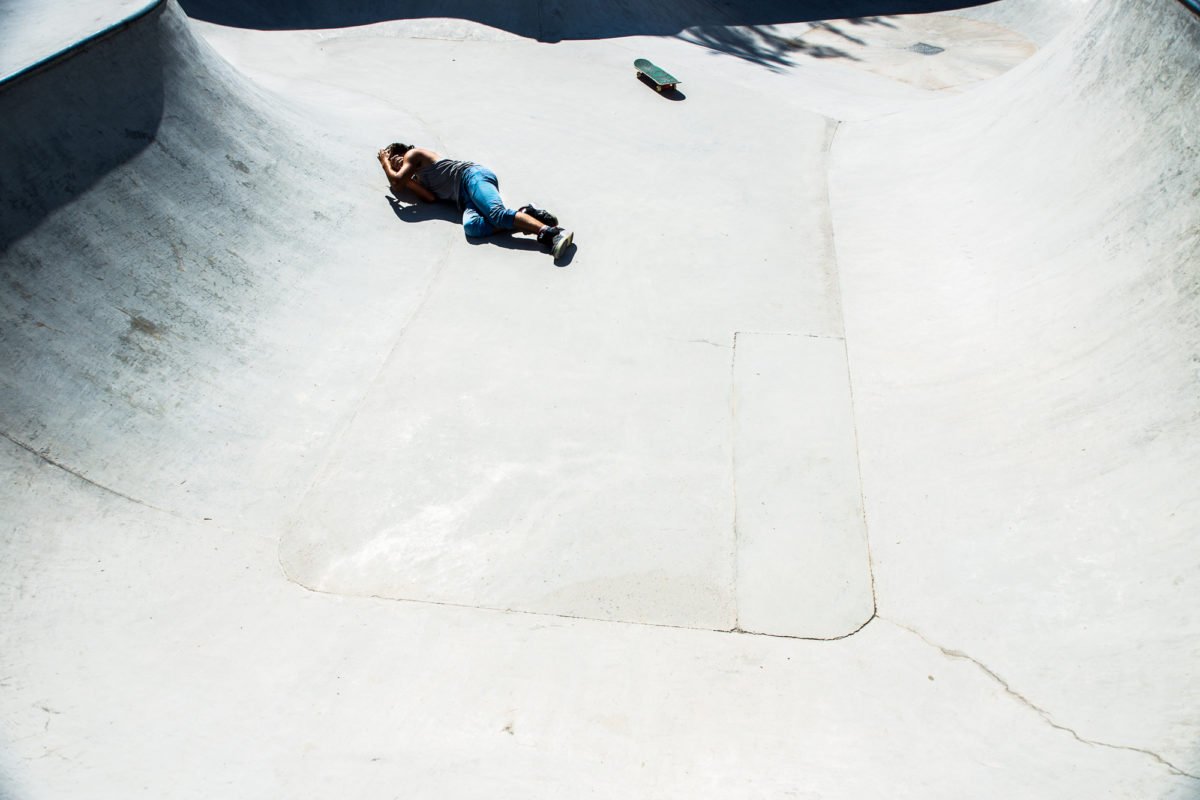 Une personne allongée sur le sol d'un bowl de skateboard dans un skatepark.