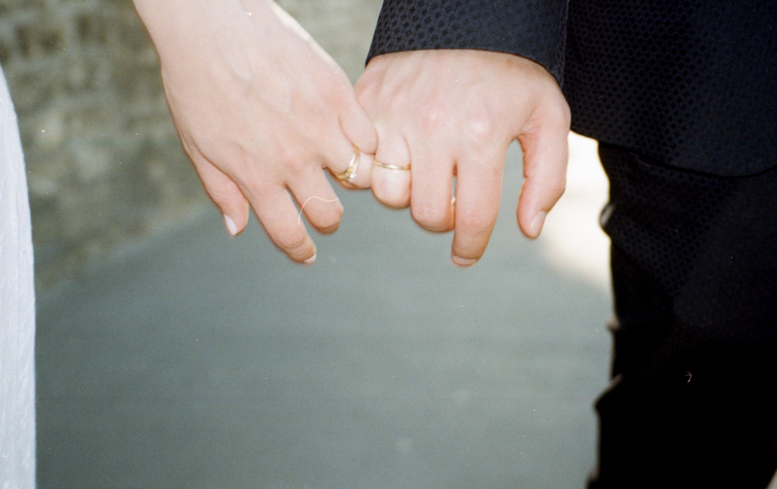 Deux personnes se tiennent par la main, portant des alliances, symbolisant l'engagement et l'amour.