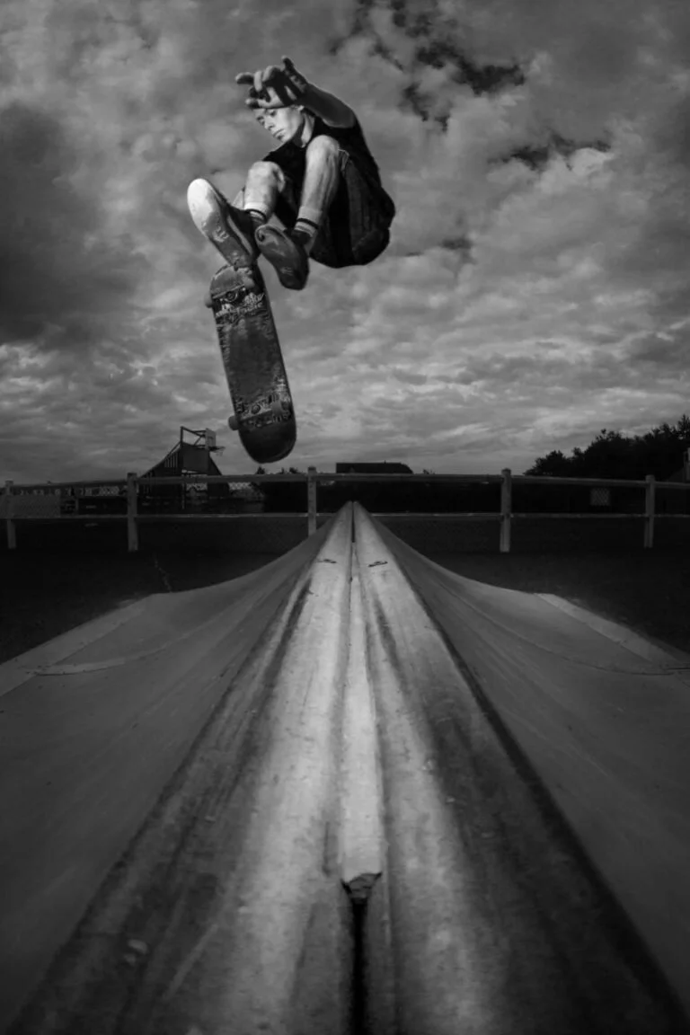Skateboardeur effectuant un trick en saut dans un skatepark en noir et blanc.