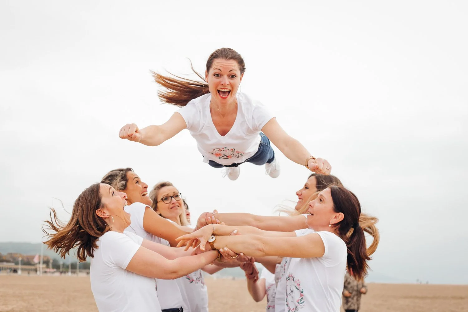 Groupe de femmes qui s'amusent à faire une levée en l'air sur la plage un jour venteux.