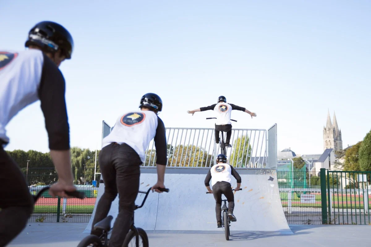 Photomontage d'un homme pratiquant le BMX dans un skatepark avec une rampe en métal, sous un ciel clair, avec une église en arrière-plan.
