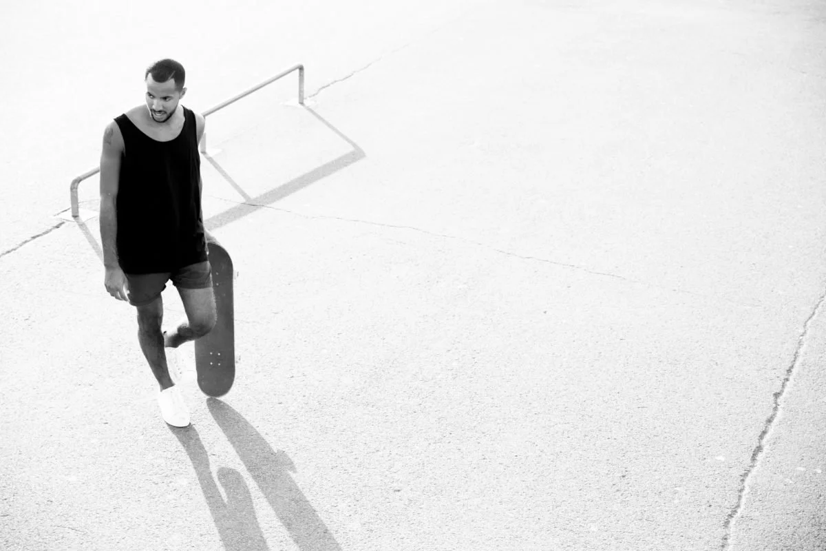 Jeune homme avec un skateboard dans un espace extérieur à Deauville, en noir et blanc.