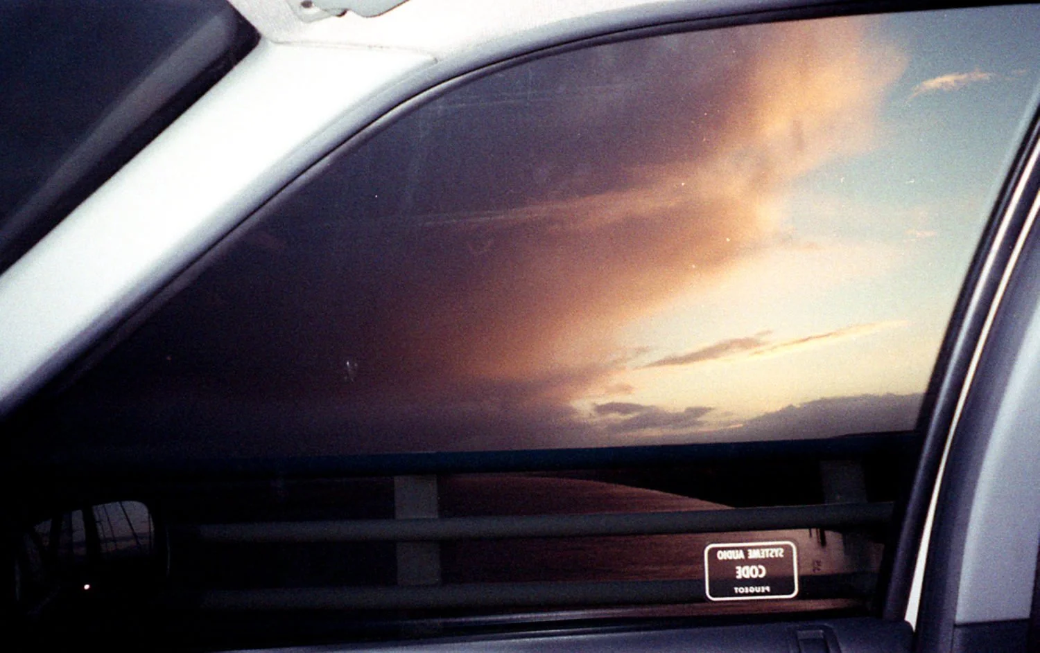 Vue d'un ciel nuageux au coucher du soleil vue depuis l'intérieur d'une voiture, à travers le pare-brise.