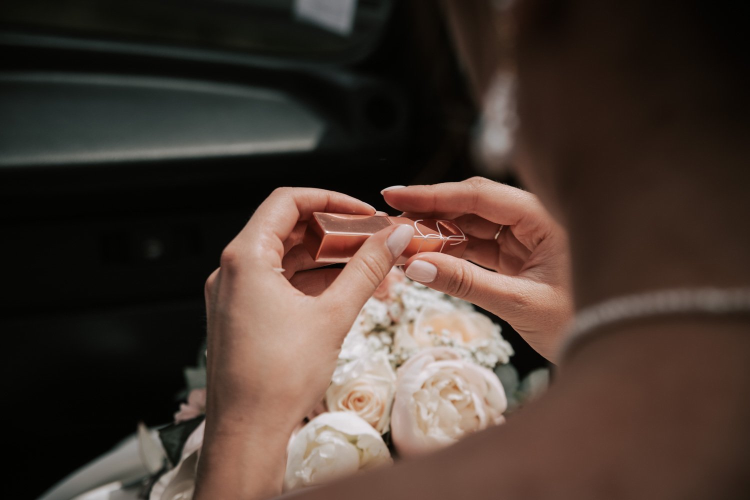 Une femme tenant un petit bijou ou une boîte à bijoux dorée, avec un bouquet de roses blanches en arrière-plan.