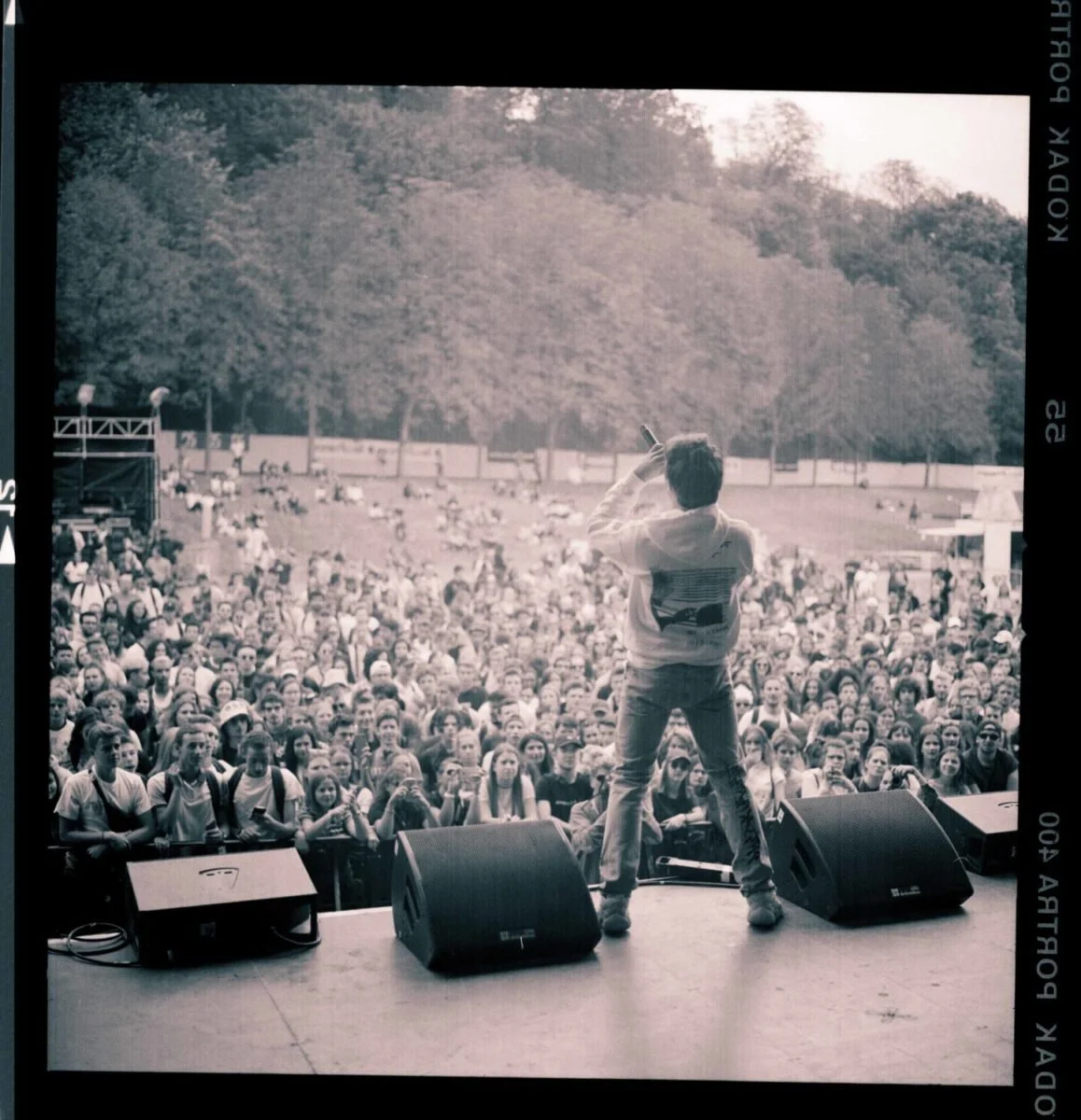 Lord Esperanza se produit à rock en seine devant une grande foule lors d'un concert en plein air, avec des arbres en arrière-plan.