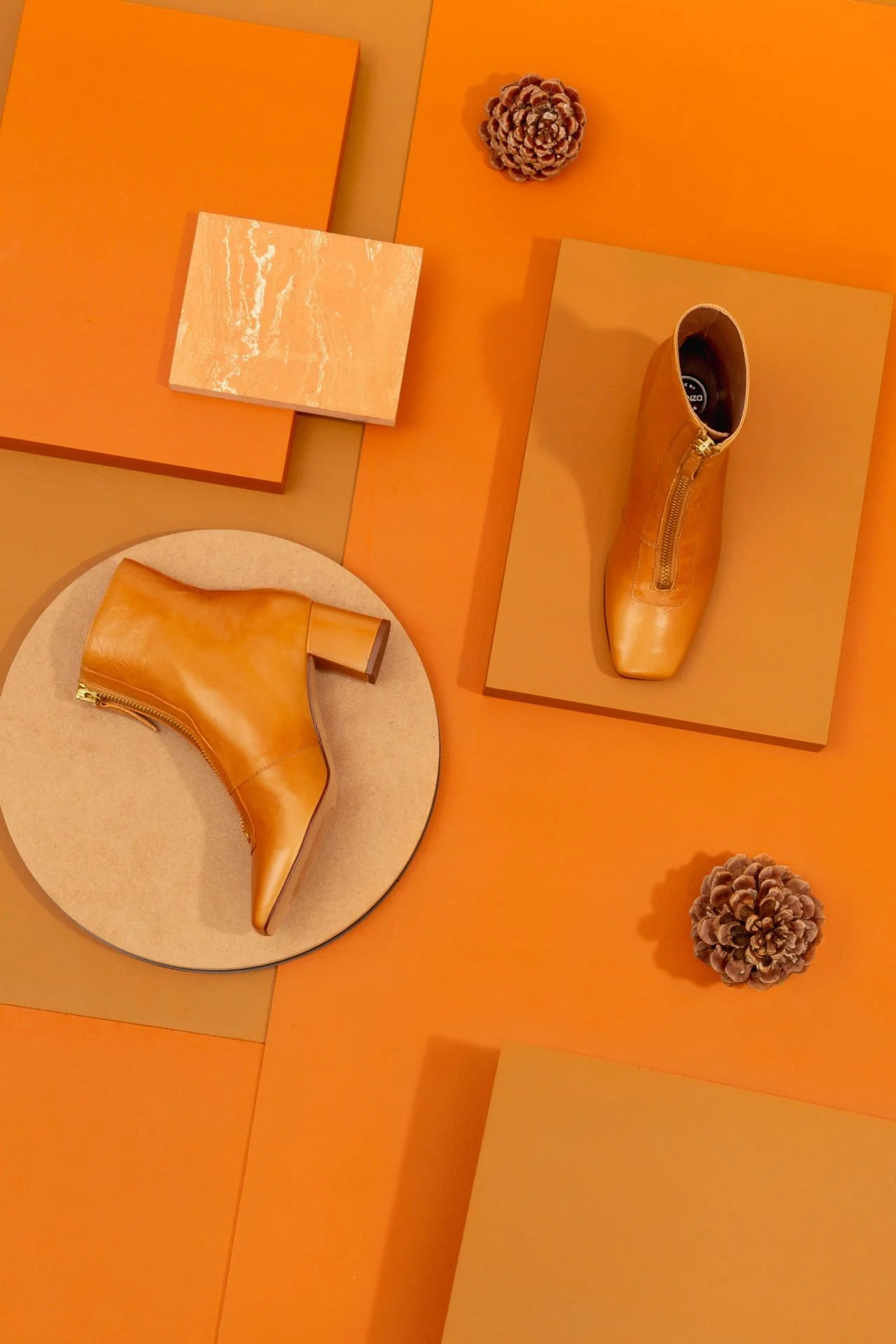 Chaussures en cuir beige avec talon carré sur différentes surfaces orange avec des pommes de pin et des blocs en bois