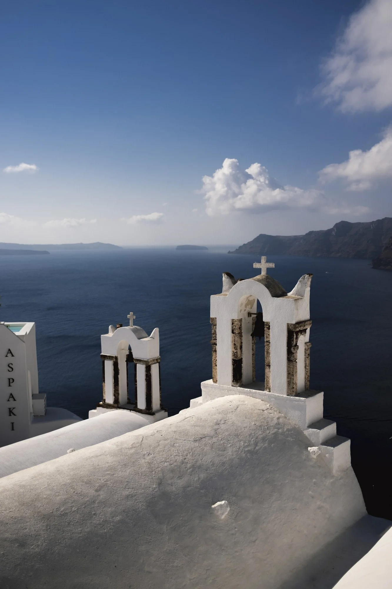 Ciel bleu avec quelques nuages au-dessus de l'océan, vue de toits blancs de bâtiments traditionnels en Santorin, Grèce.