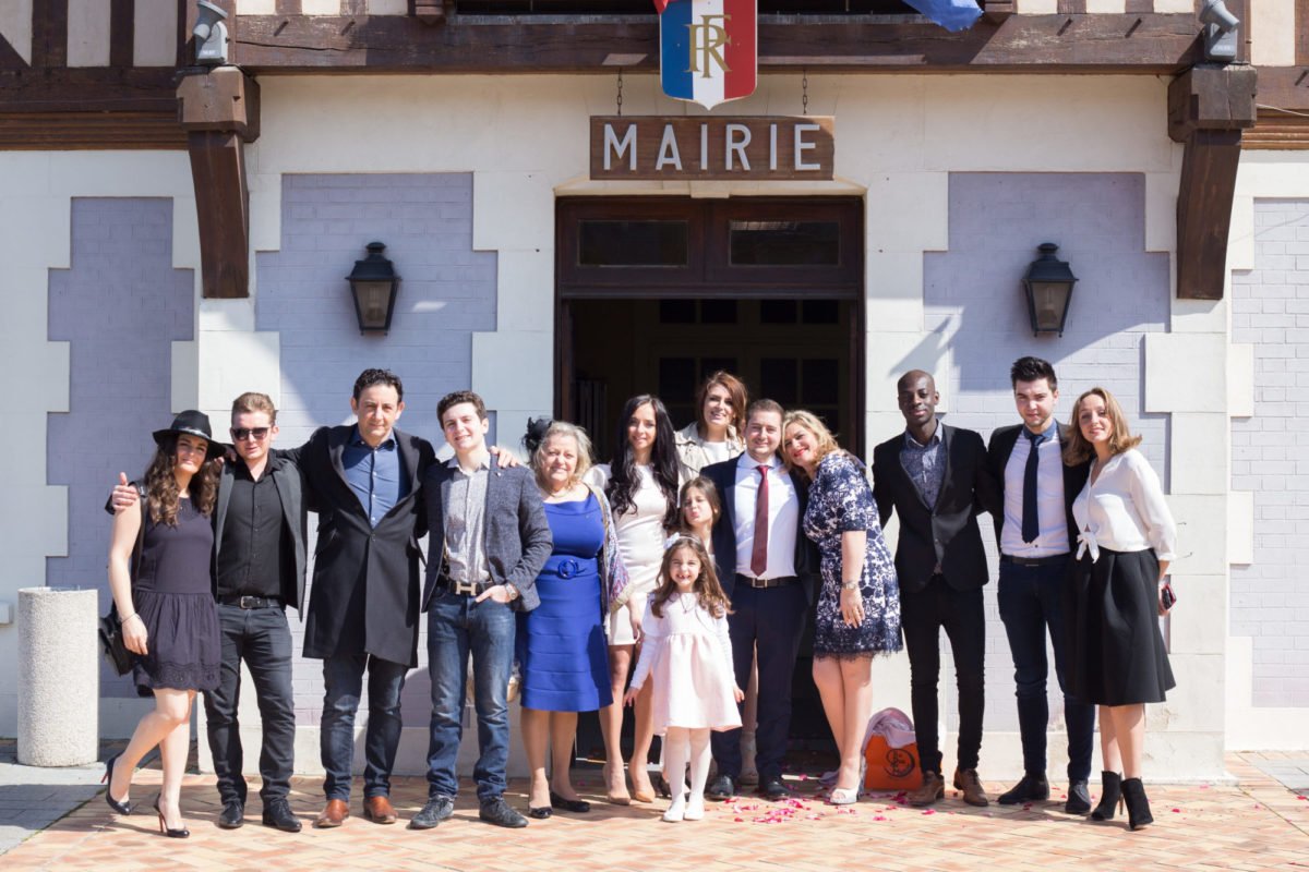 Groupe de personnes posant devant la mairie, avec un panneau indiquant 'MAIRIE' au-dessus de l'entrée.