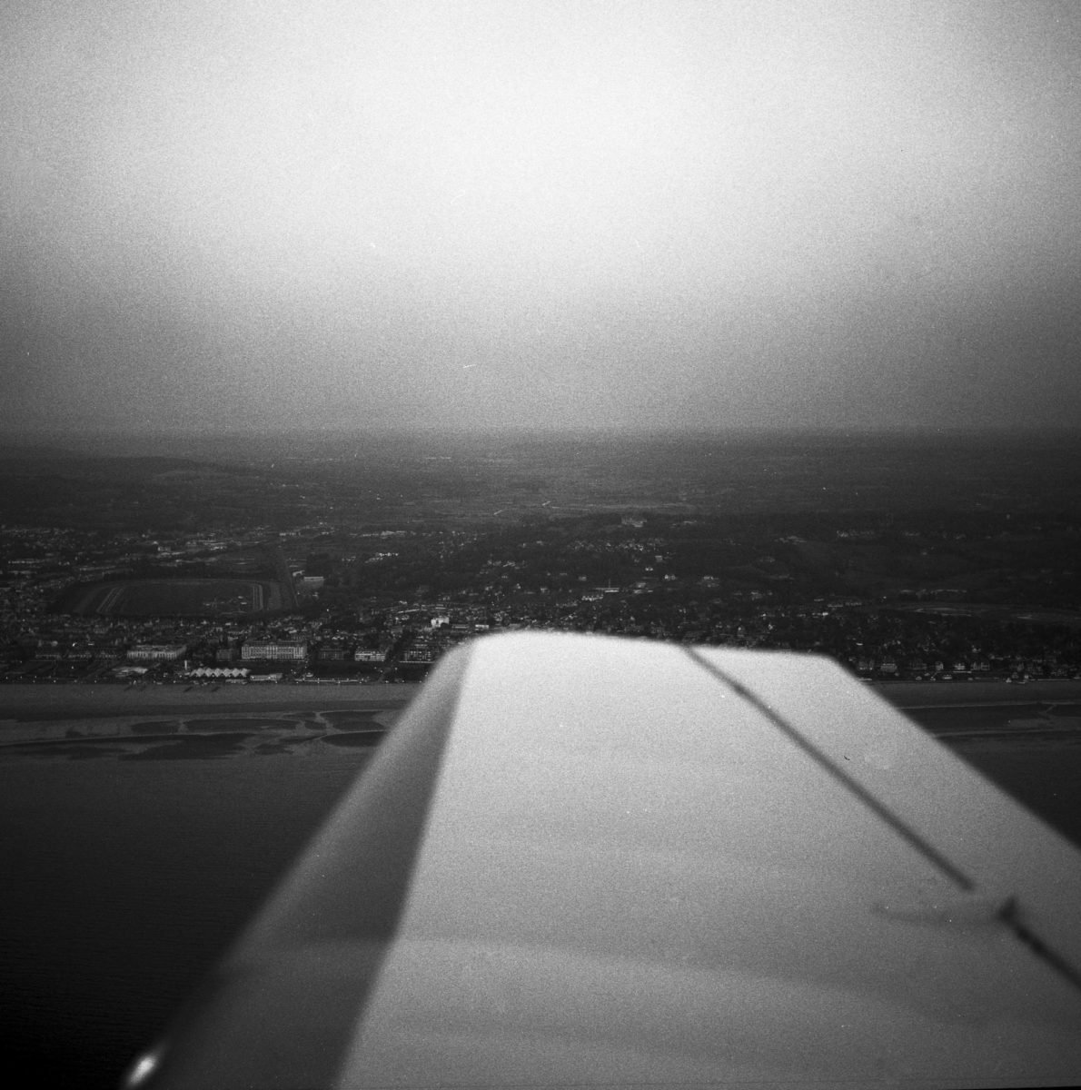 Vue aérienne d'une ville vue depuis un avion, en noir et blanc.